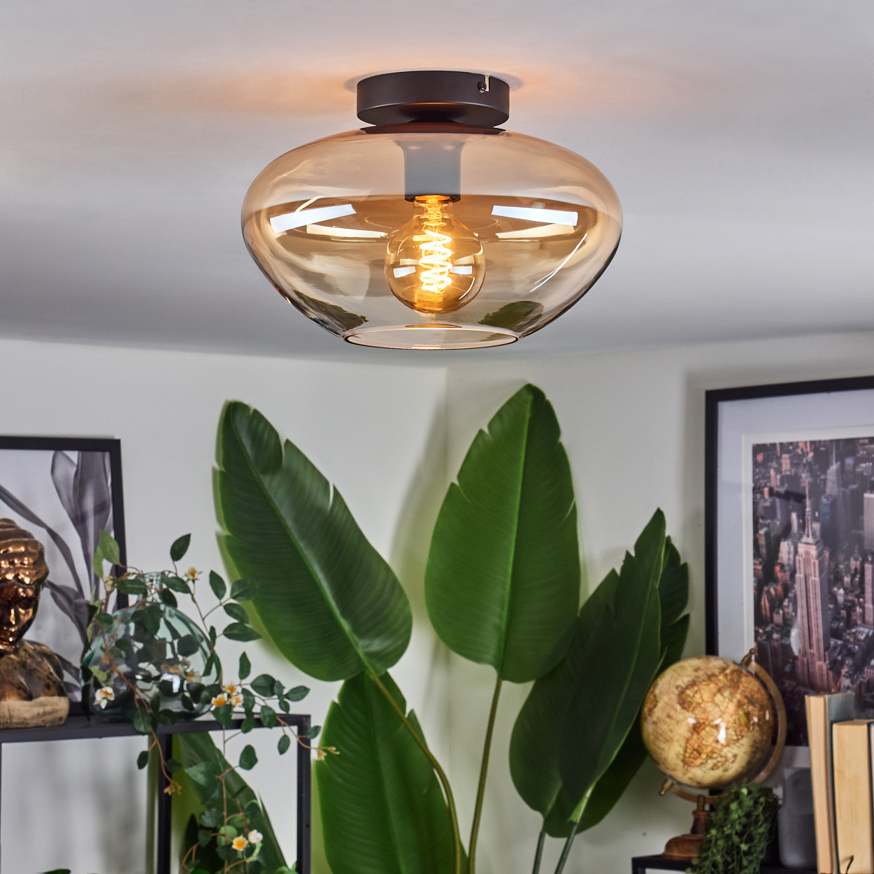 Deckenlampe mit bernsteinfarbenem Glasschirm, schwarzem Sockel und Raumdekor.