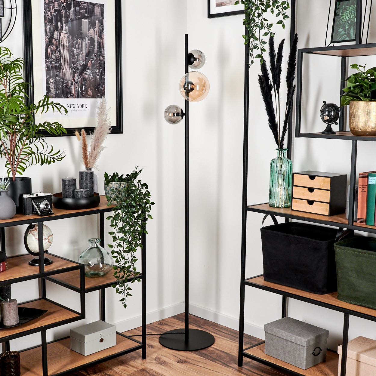 Ein Zimmer mit Stehlampe, Regalen und Dekoration. Ein New York-Poster und ein schwarzer Schrank sind ebenfalls zu sehen.
