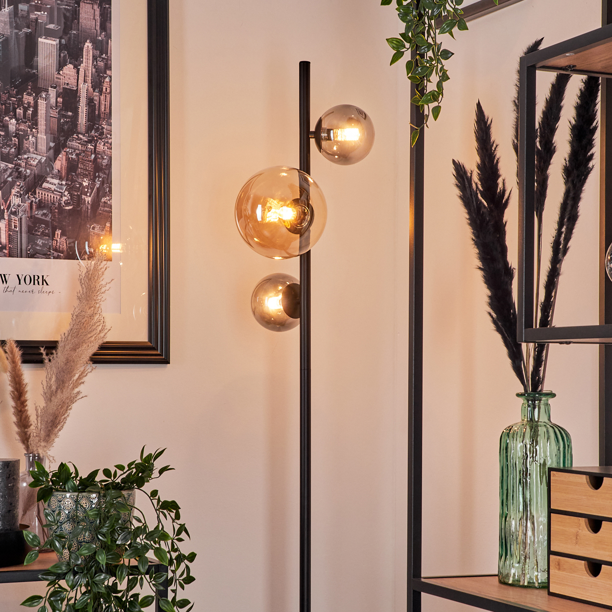 Interieur mit Stehlampe, Pflanzen und Regalen, das eine warme, einladende Atmosphäre schafft.