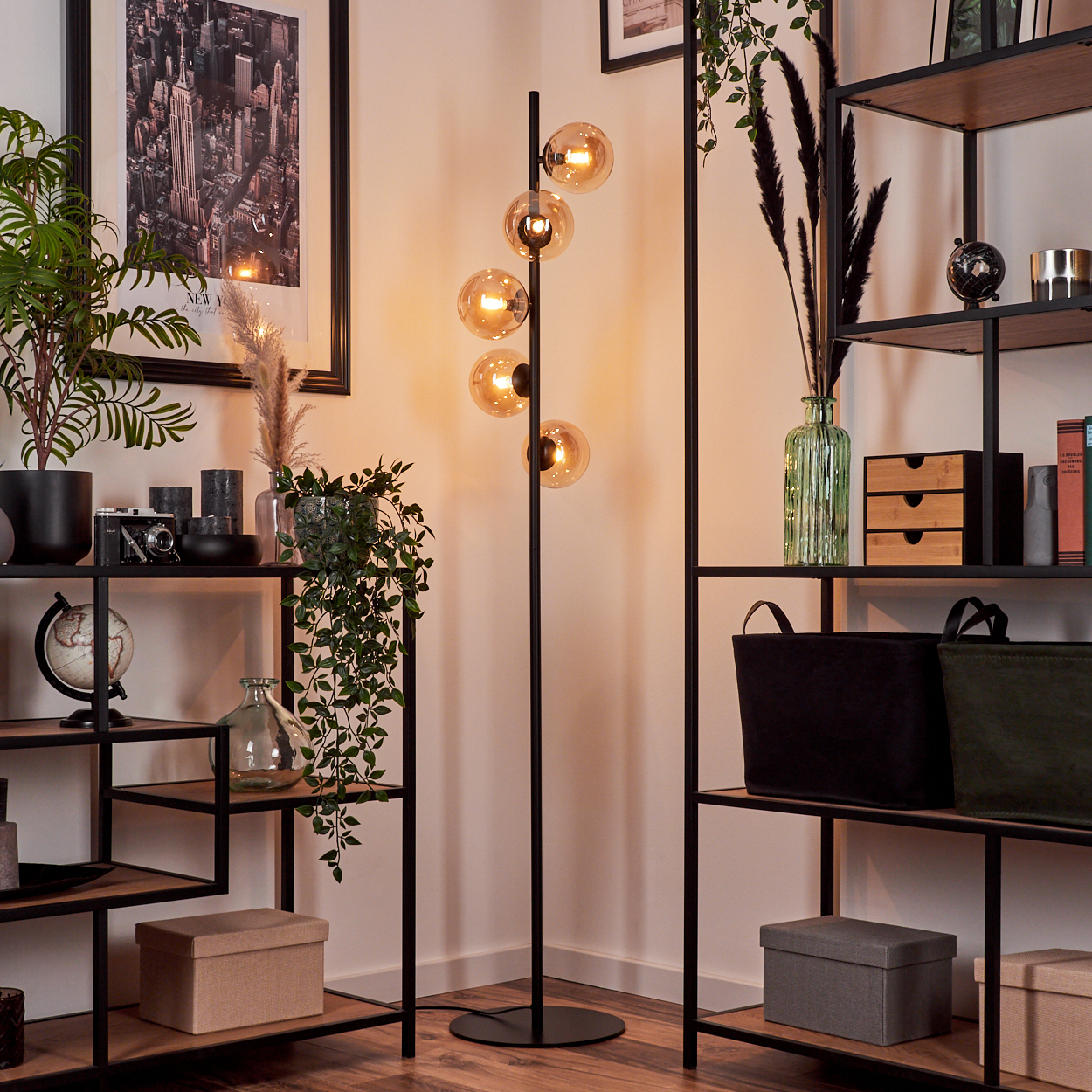 Eine Stehlampe mit fünf bernsteinfarbenen Glaskugeln und Regalen mit Dekoration.