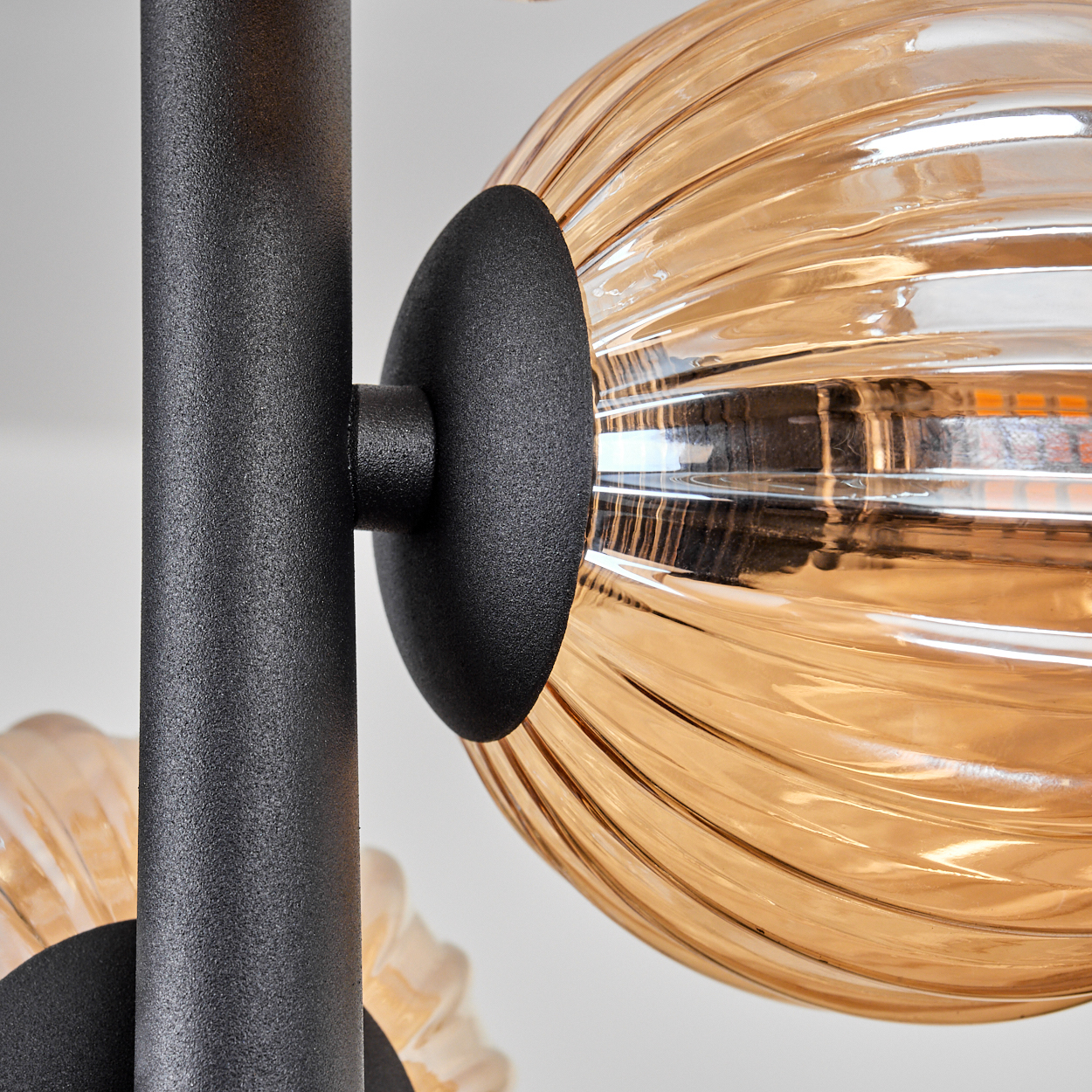 Nahaufnahme einer schwarzen Metallvorrichtung mit einem orangefarbenen Glaskugel.
