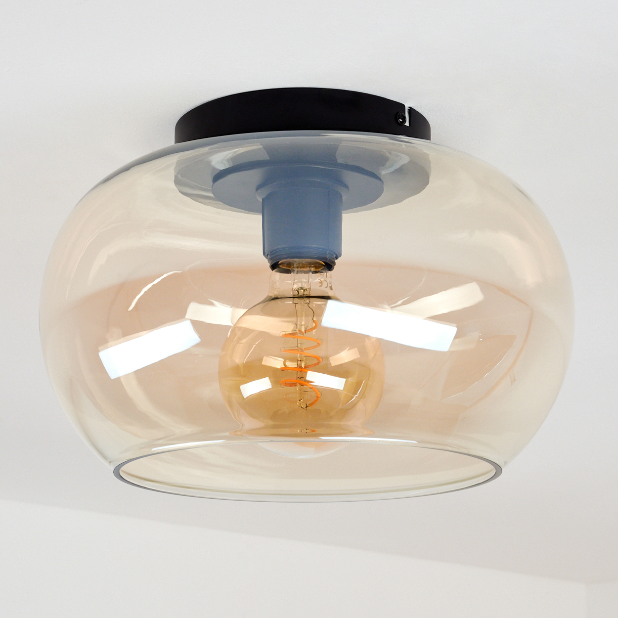 Eine Deckenlampe mit Glasschirm. Eine Glühbirne befindet sich im Inneren des Schirms.