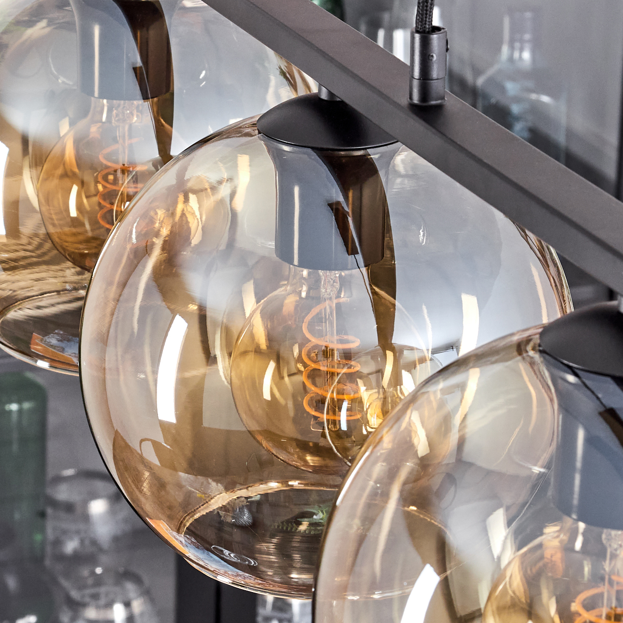 Nahaufnahme von drei bernsteinfarbenen Glas-Hängeleuchten. Der Hintergrund ist eine verschwommene Anzeige.