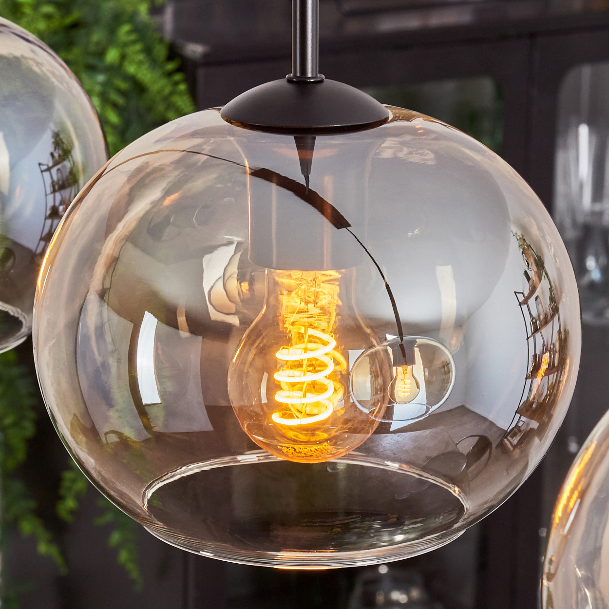 Nahaufnahme einer Glas-Pendelleuchte. Ein Wendelfaden ist im Inneren des Glaskolbens sichtbar.