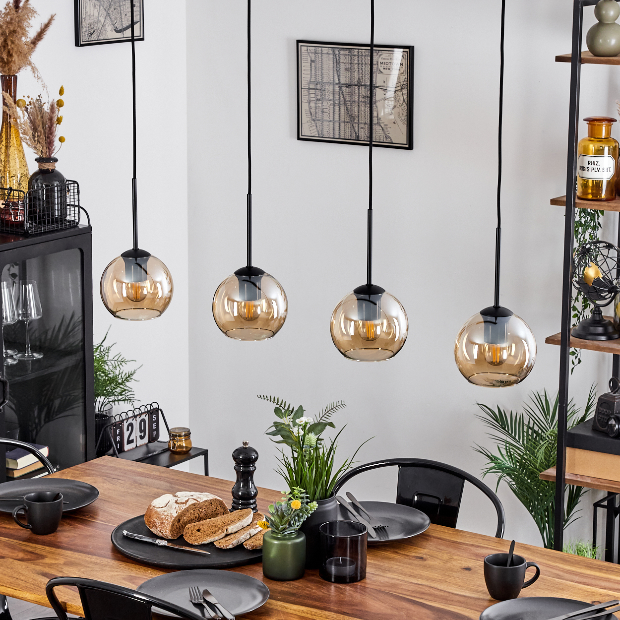 Esszimmer mit vier Pendelleuchten über einem Holztisch. Teller, Essen und Dekoration sind vorhanden.