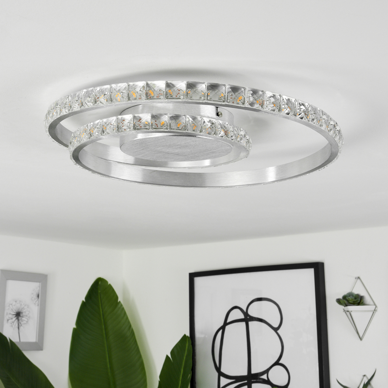 Deckenleuchte mit Spiraldesign, vor weißem Hintergrund mit Pflanzen.