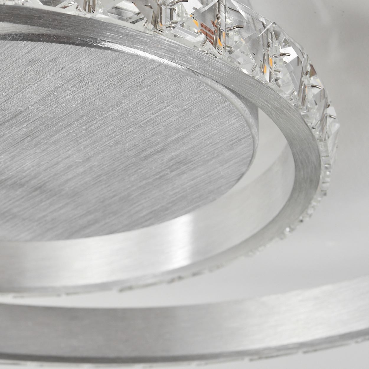 Nahaufnahme eines silbernen Metallrings mit klaren Kristallen, der ein dekoratives Lichtelement bildet.