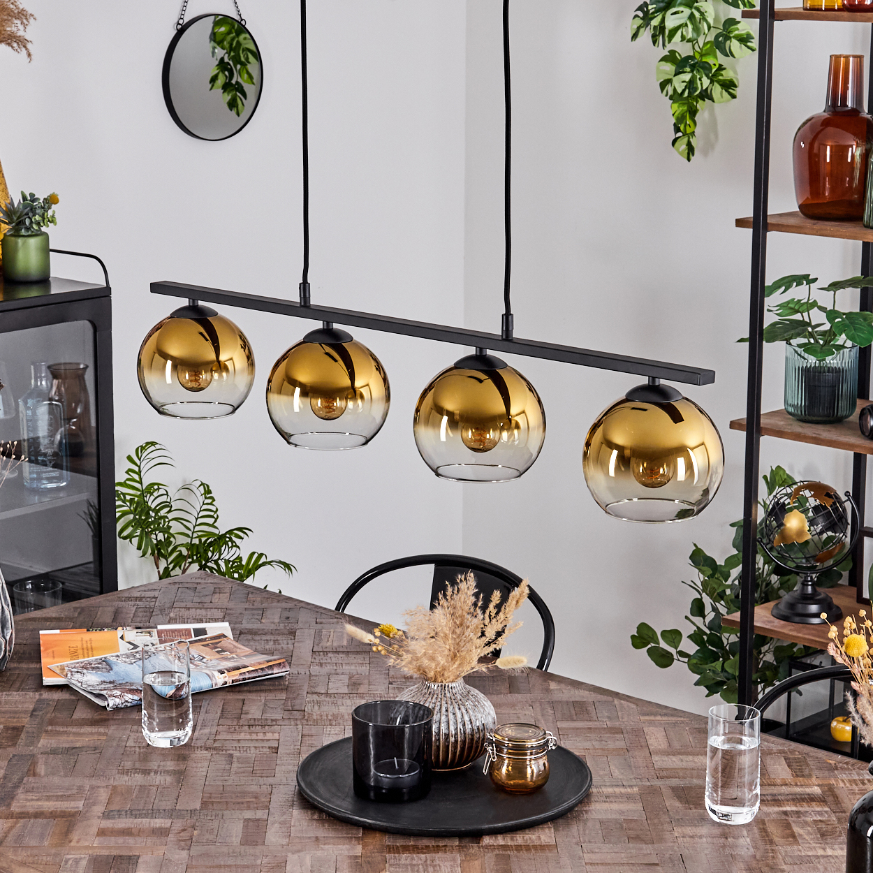 Esszimmer mit vier Pendelleuchten. Holztisch mit Geschirr, Deko und schwarzem Stuhl sichtbar.