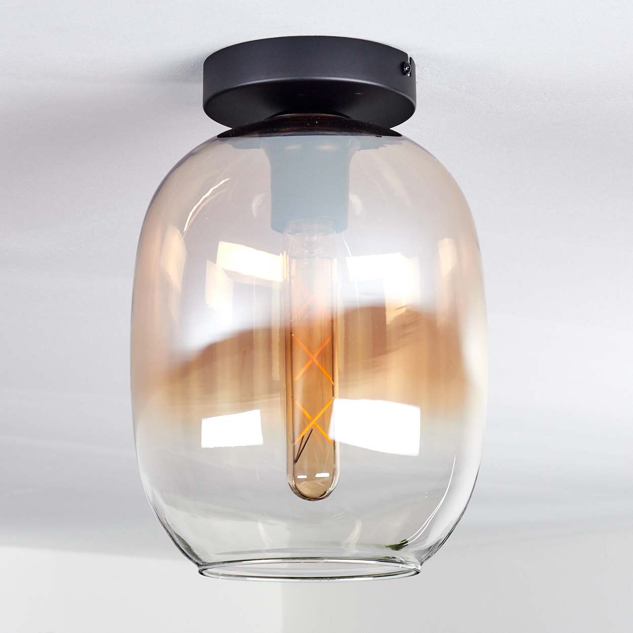 Eine Deckenlampe mit einem Glasschirm in hellbrauner Farbe. Eine klare Glühbirne im Inneren.