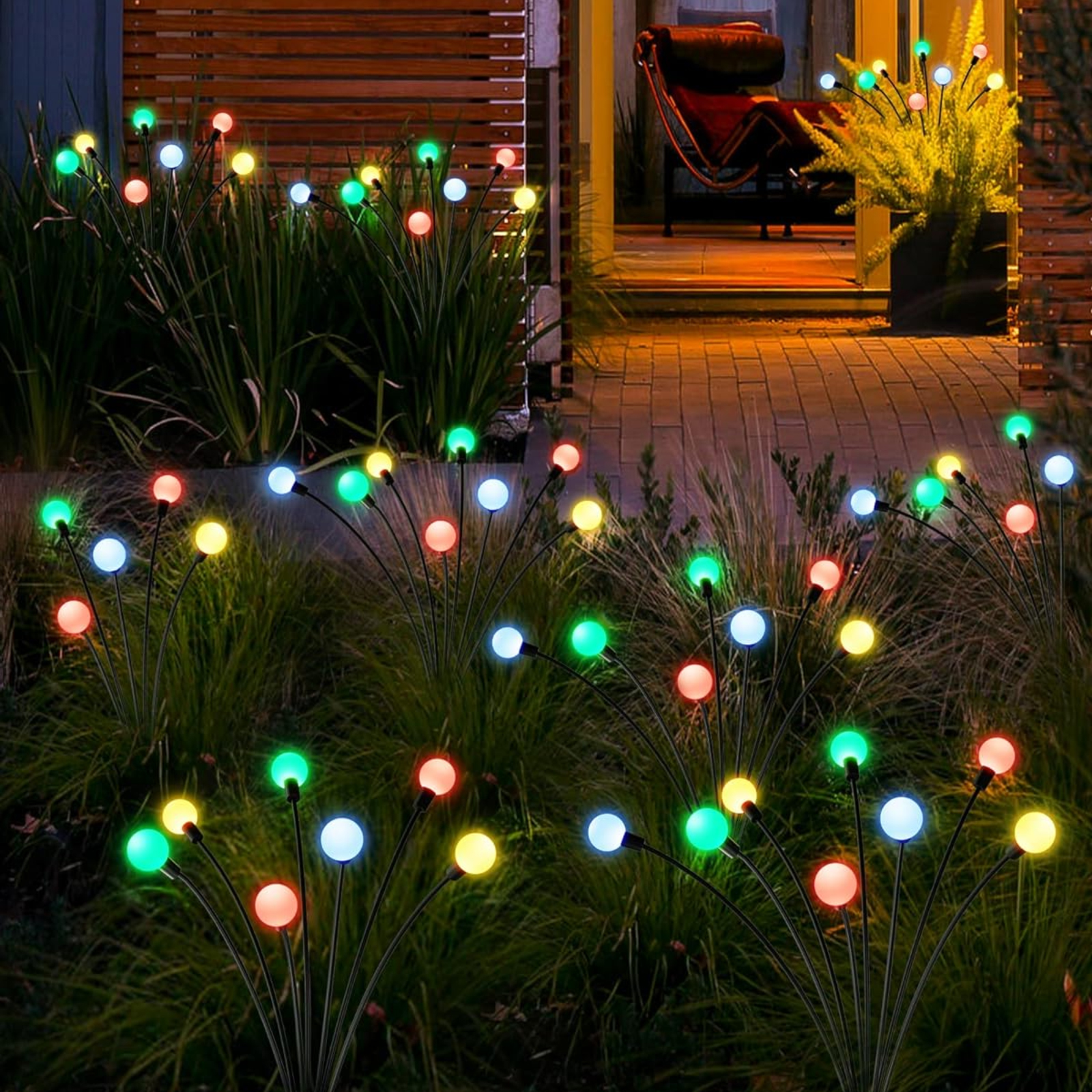 Außen-Gartenleuchten mit farbigen Glühbirnen. Die Lichter befinden sich in der Nähe des Rasens und eines Hauses.