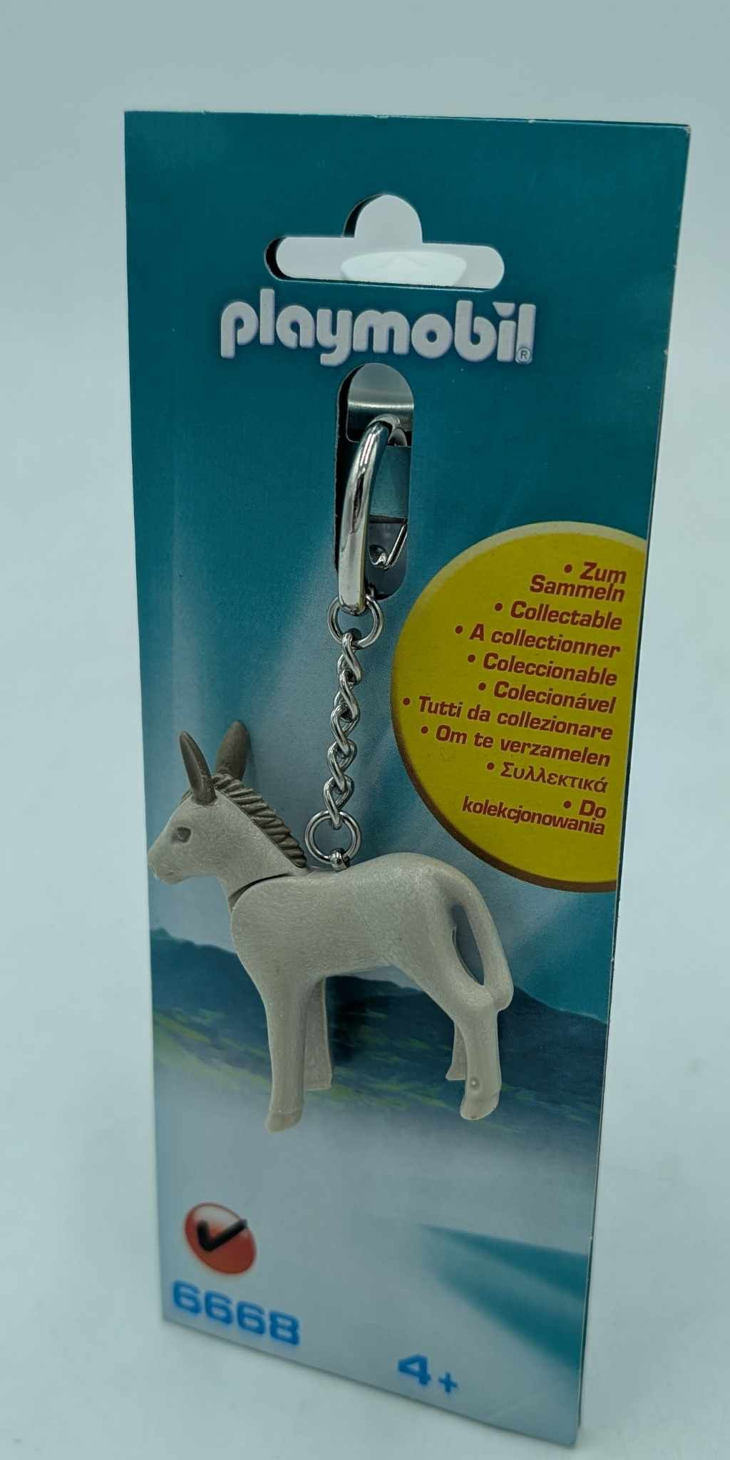 Un portachiavi Playmobil di un asino bianco, appeso a una carta blu e bianca.