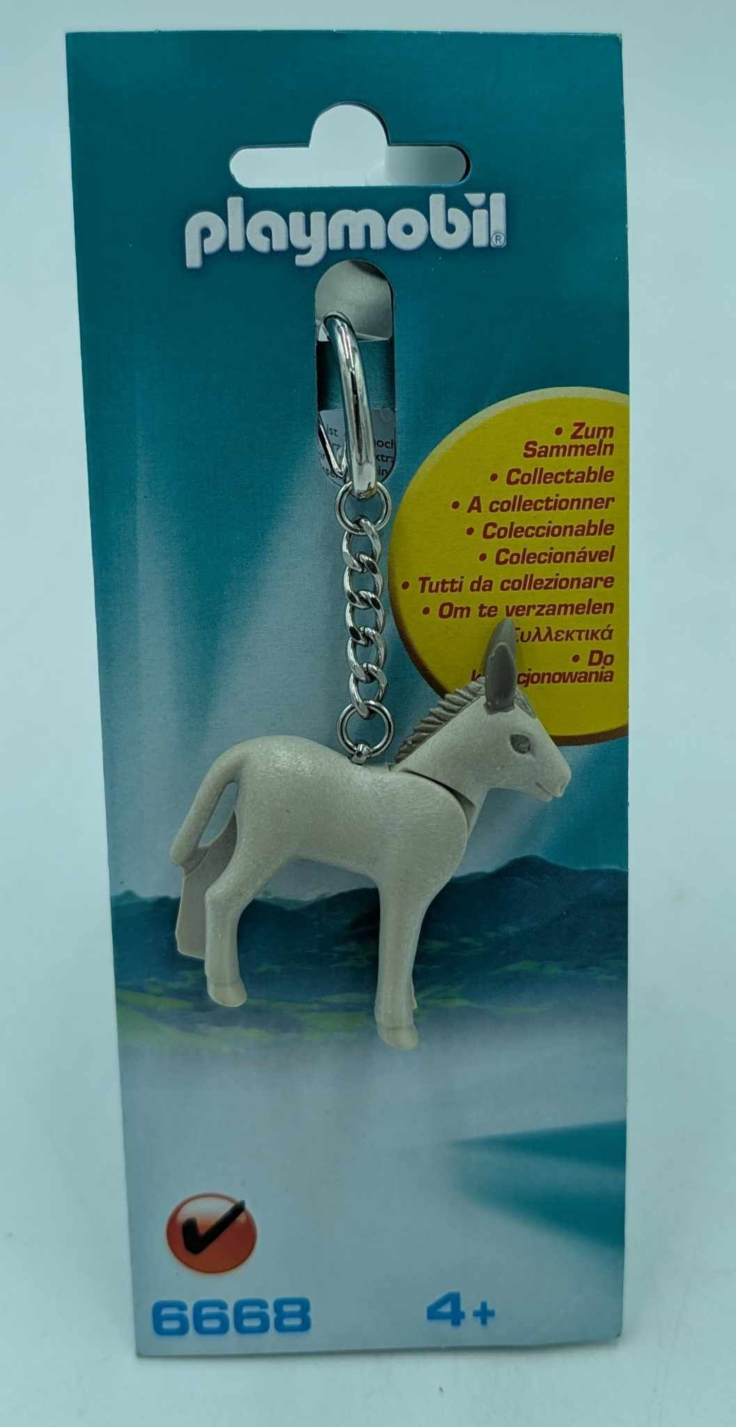 Un portachiavi Playmobil di un asino bianco, appeso a una carta blu e bianca.