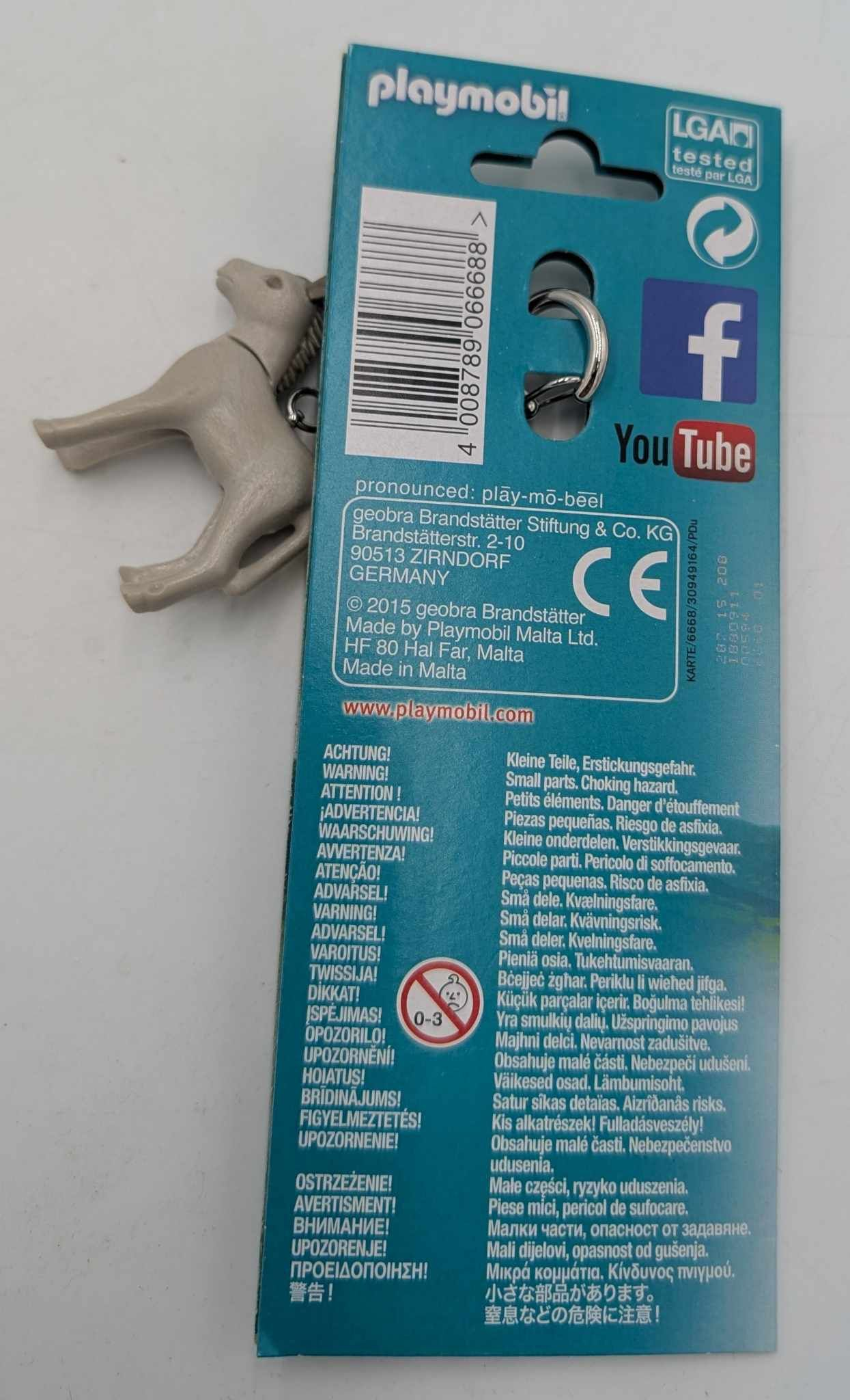 Il retro di un portachiavi Playmobil, con una figura di asino grigio e informazioni sul prodotto.