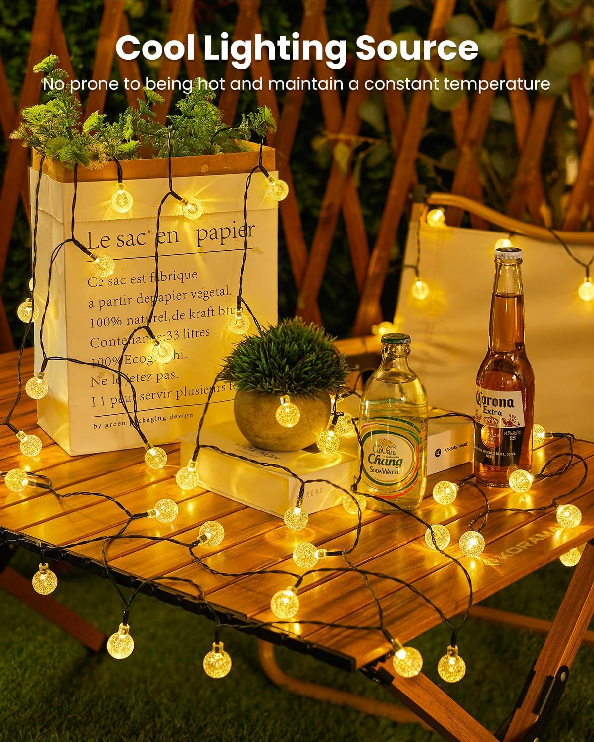 Tisch mit Lichterketten. Bierflaschen und Snacks. Weiße Papiertüte und Pflanze, Holztisch.