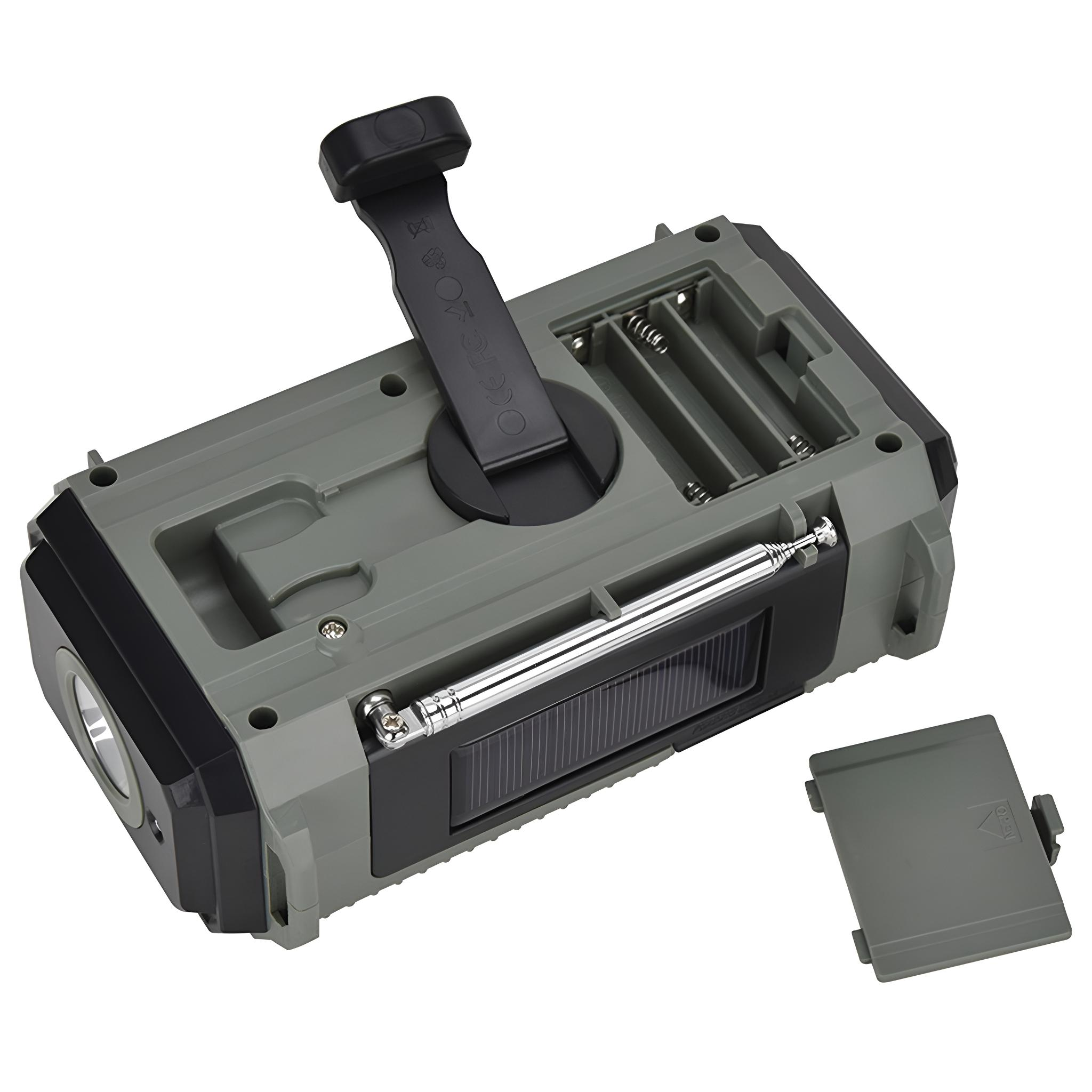 Ein grau-schwarzes Radio mit Solarpanel und Kurbel. Eine Batterieabdeckung daneben.