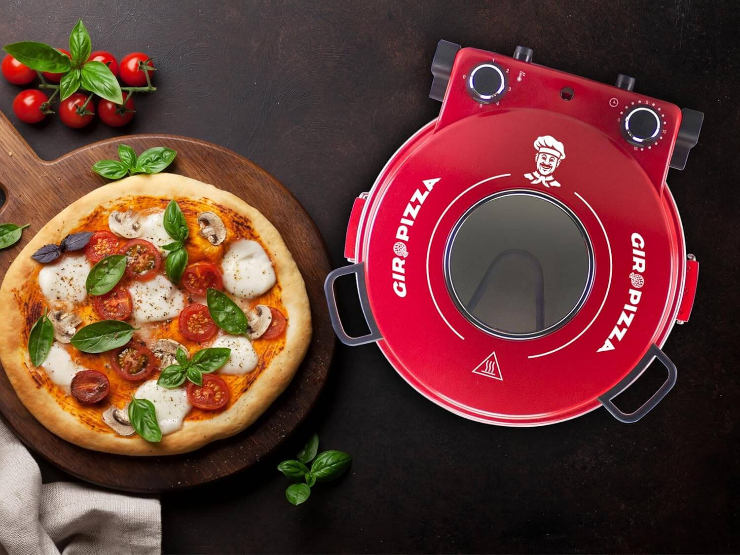 Una pizza è posta su un tagliere di legno accanto a un forno per pizza rosso su una superficie scura.