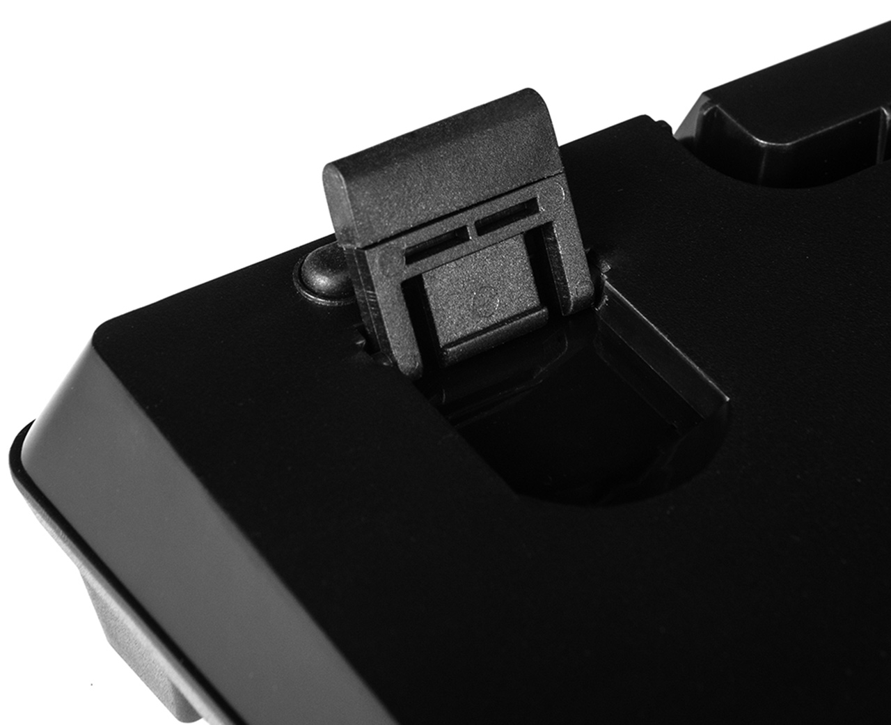 Zbliżenie czarnej podstawy klawiatury z czarnym plastikowym wspornikiem. Białe tło.