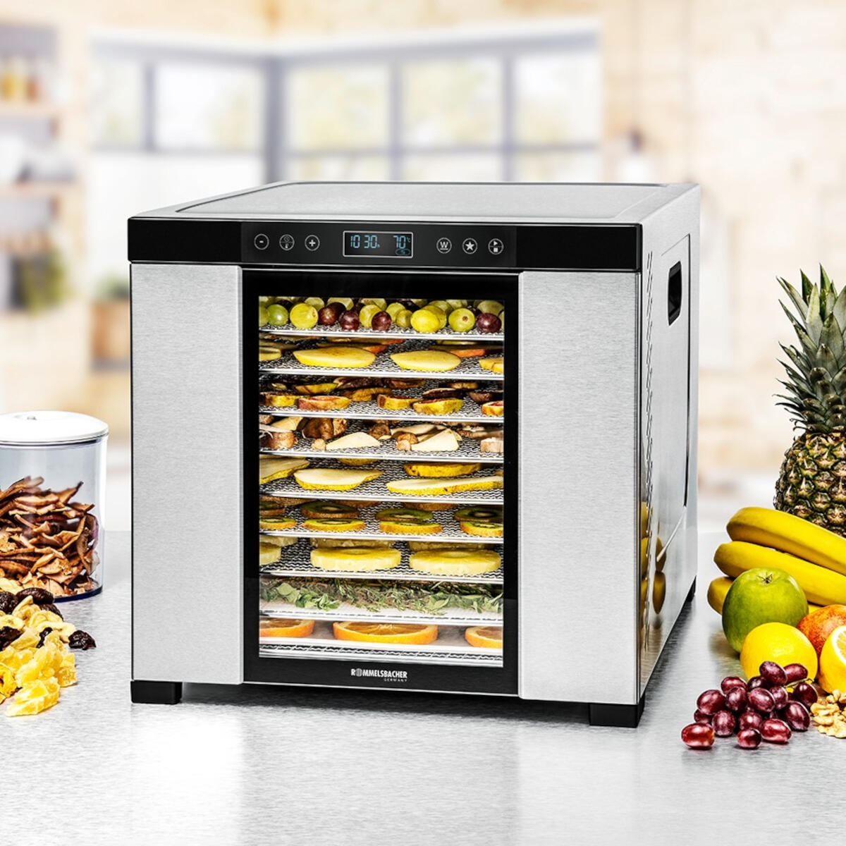 Déshydrateur alimentaire avec divers fruits et légumes séchés sur plateaux, avec un compotier.