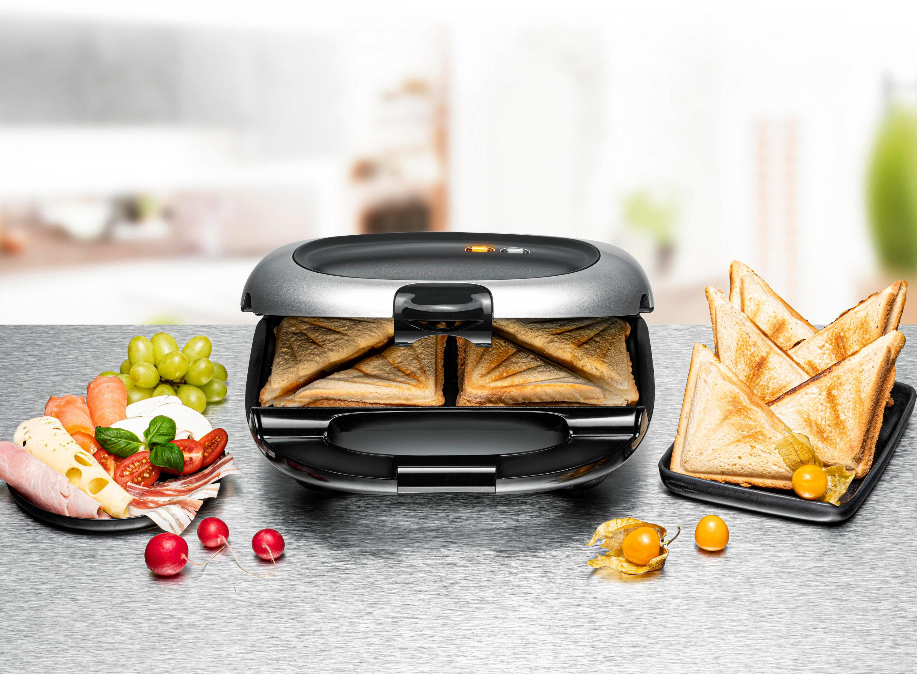 Toster do kanapek z tostowanymi kanapkami, jedzeniem na talerzach i winogronami. Tostowany chleb z owocami miechunki.