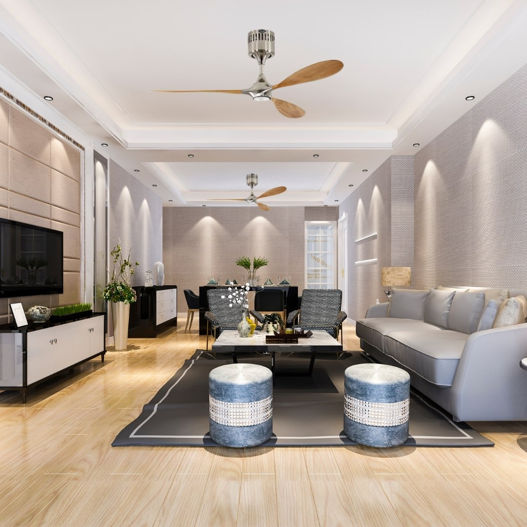 Ein modernes Wohnzimmer mit Deckenventilator, Sofa, Teppich und zwei blauen Hockern.