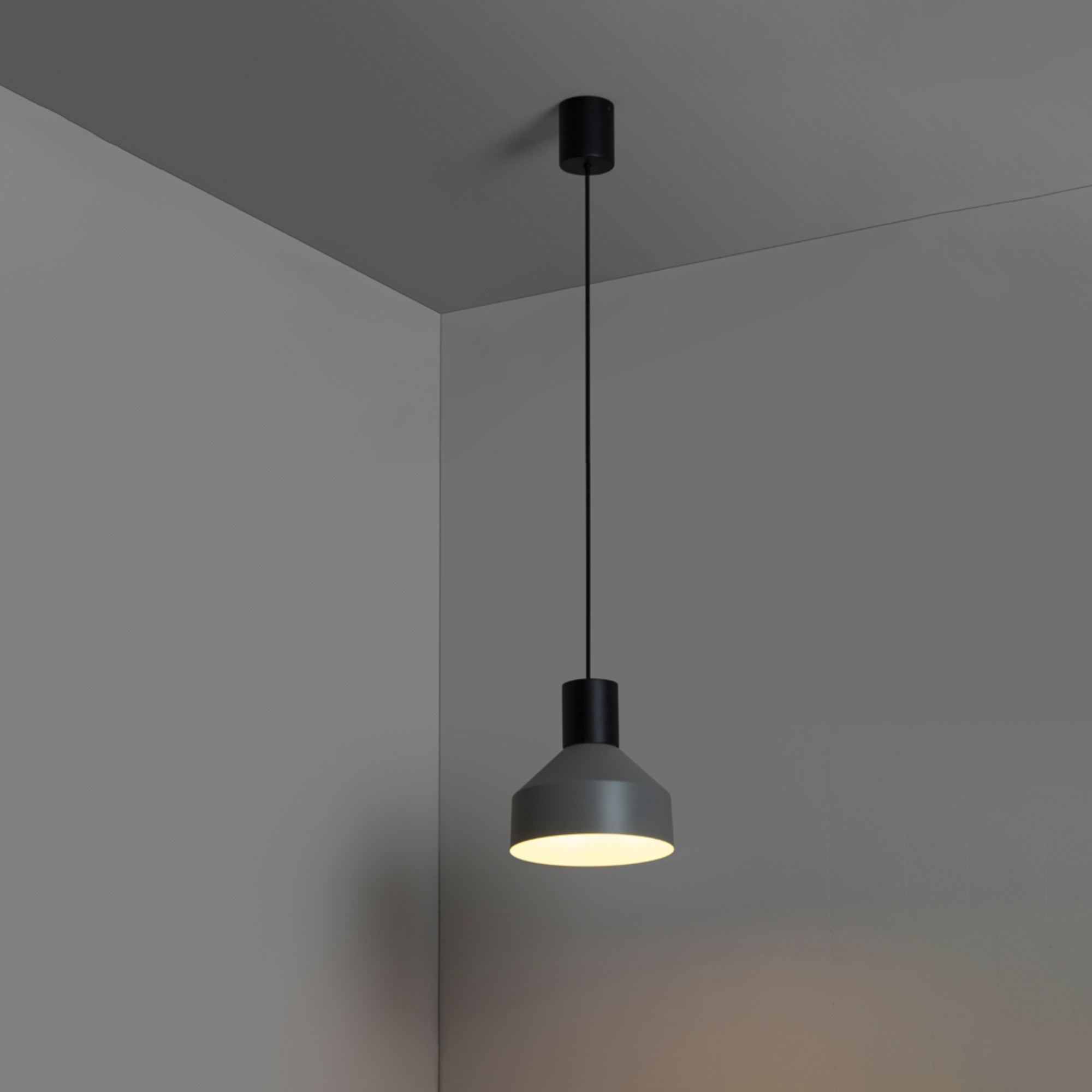 Un moderno lampadario a sospensione in un angolo grigio.