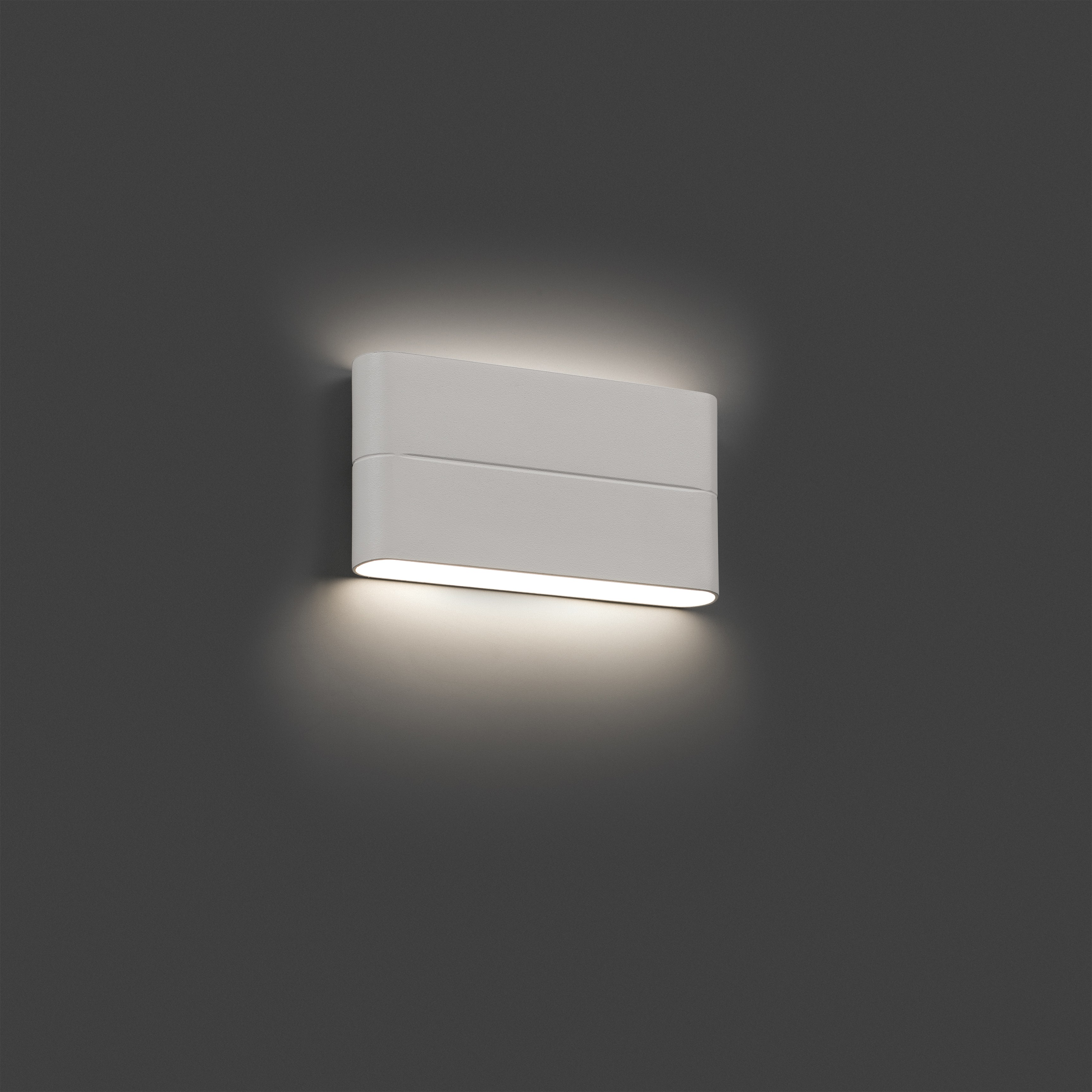 Lampada da parete rettangolare bianca. È montata su una parete grigio scuro ed emette luce verso il basso.