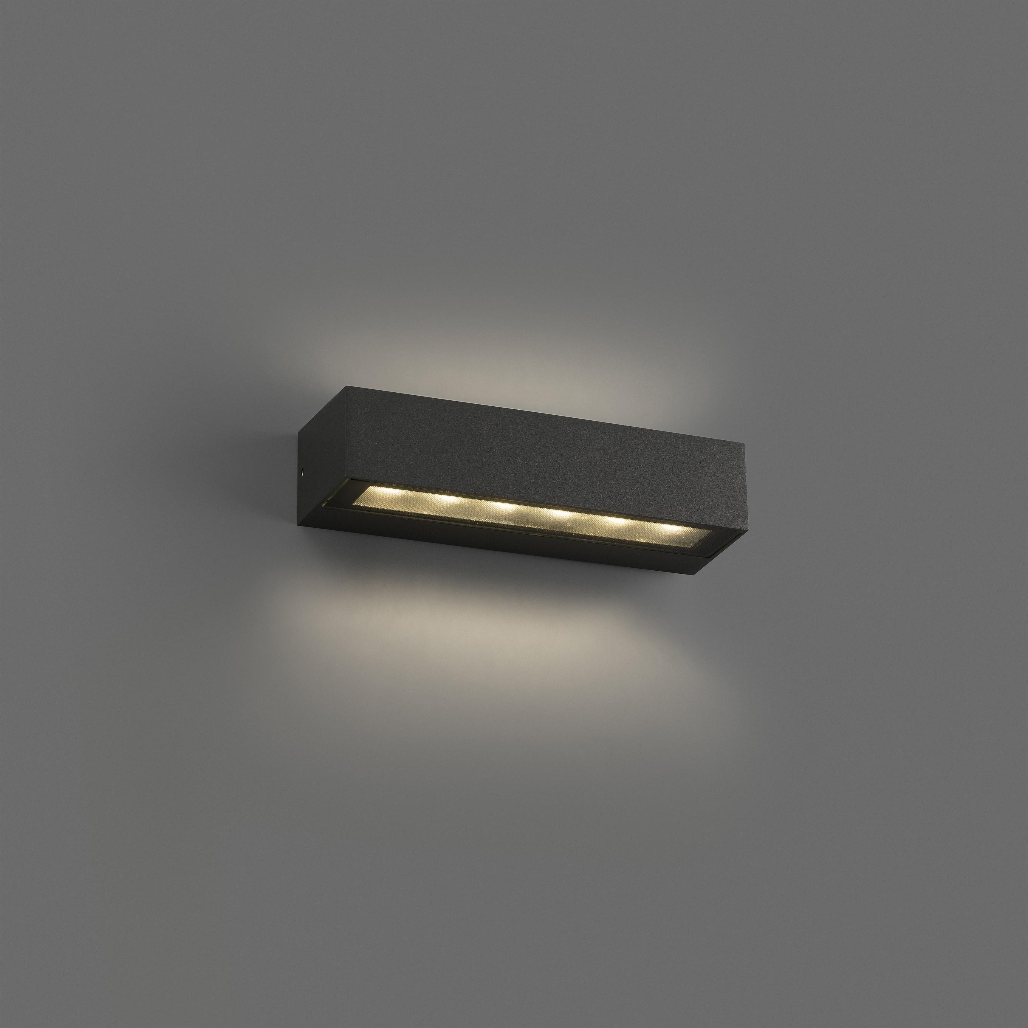 Una lampada rettangolare nera a parete su un muro grigio. La luce è accesa.