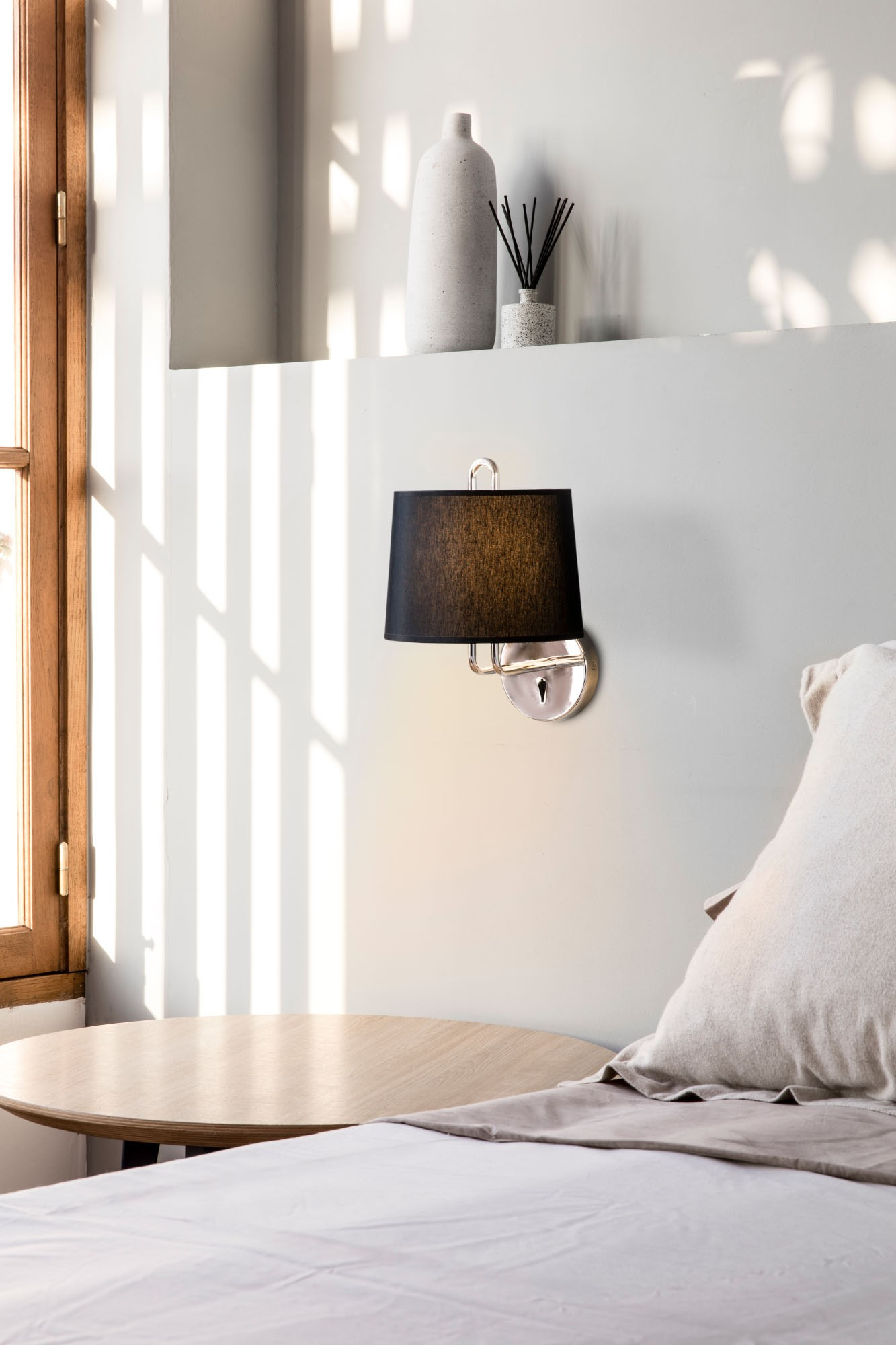 Scena della camera da letto con una lampada a parete, un letto e oggetti decorativi.