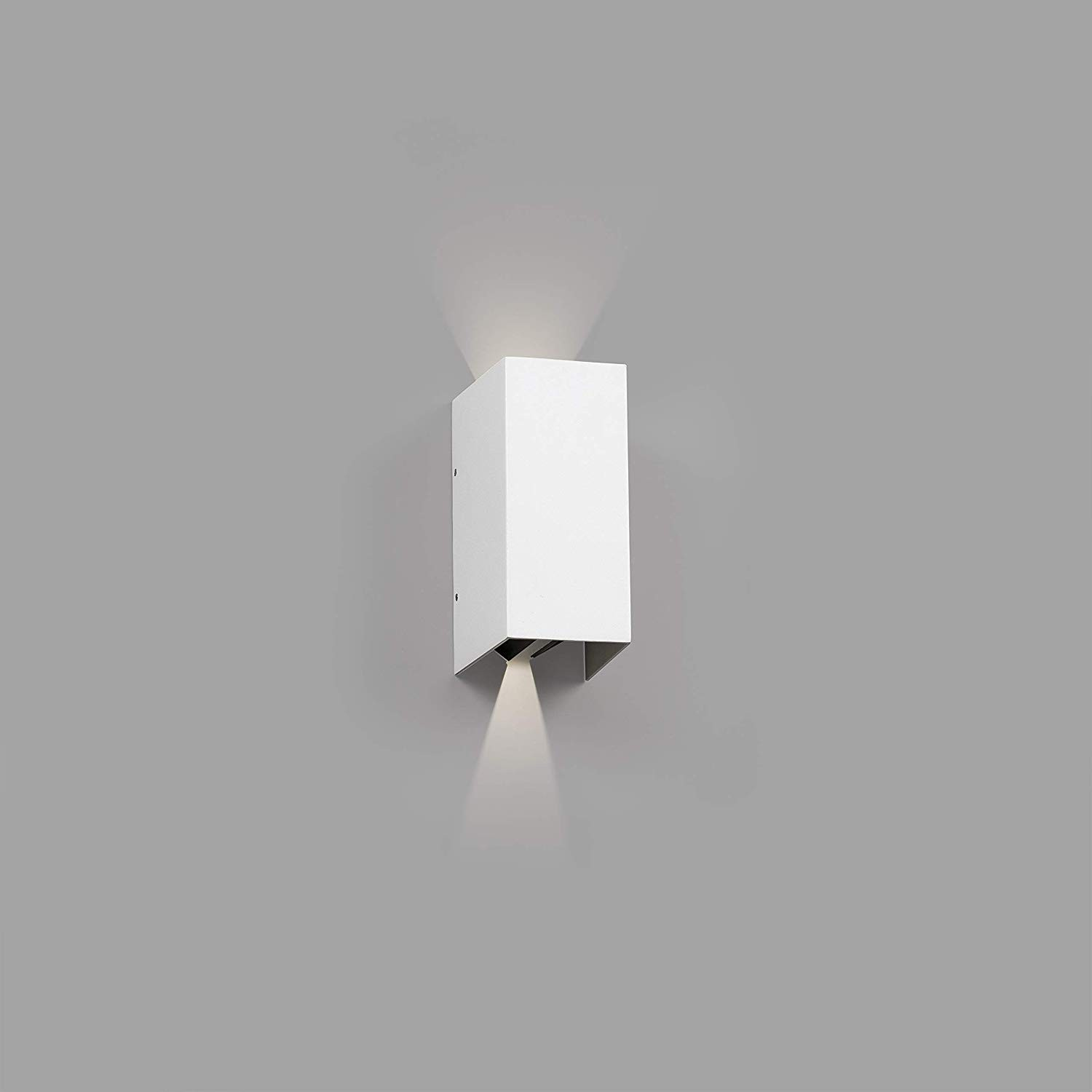 Lampada da parete rettangolare bianca su un muro grigio, che proietta la luce verso il basso e verso l'alto.