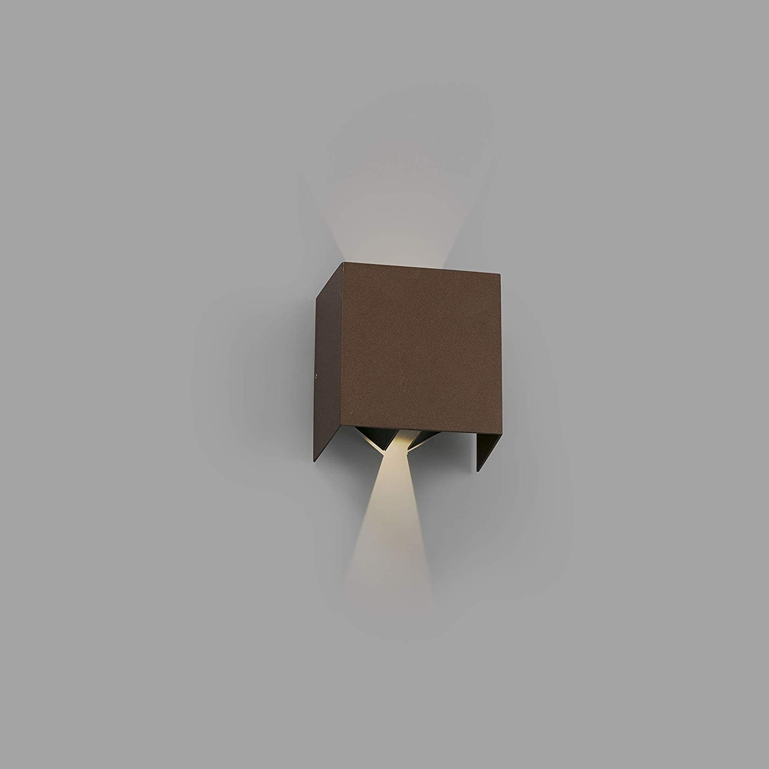 Lampada da parete a forma di cubo marrone, che proietta la luce verso il basso su un muro grigio.