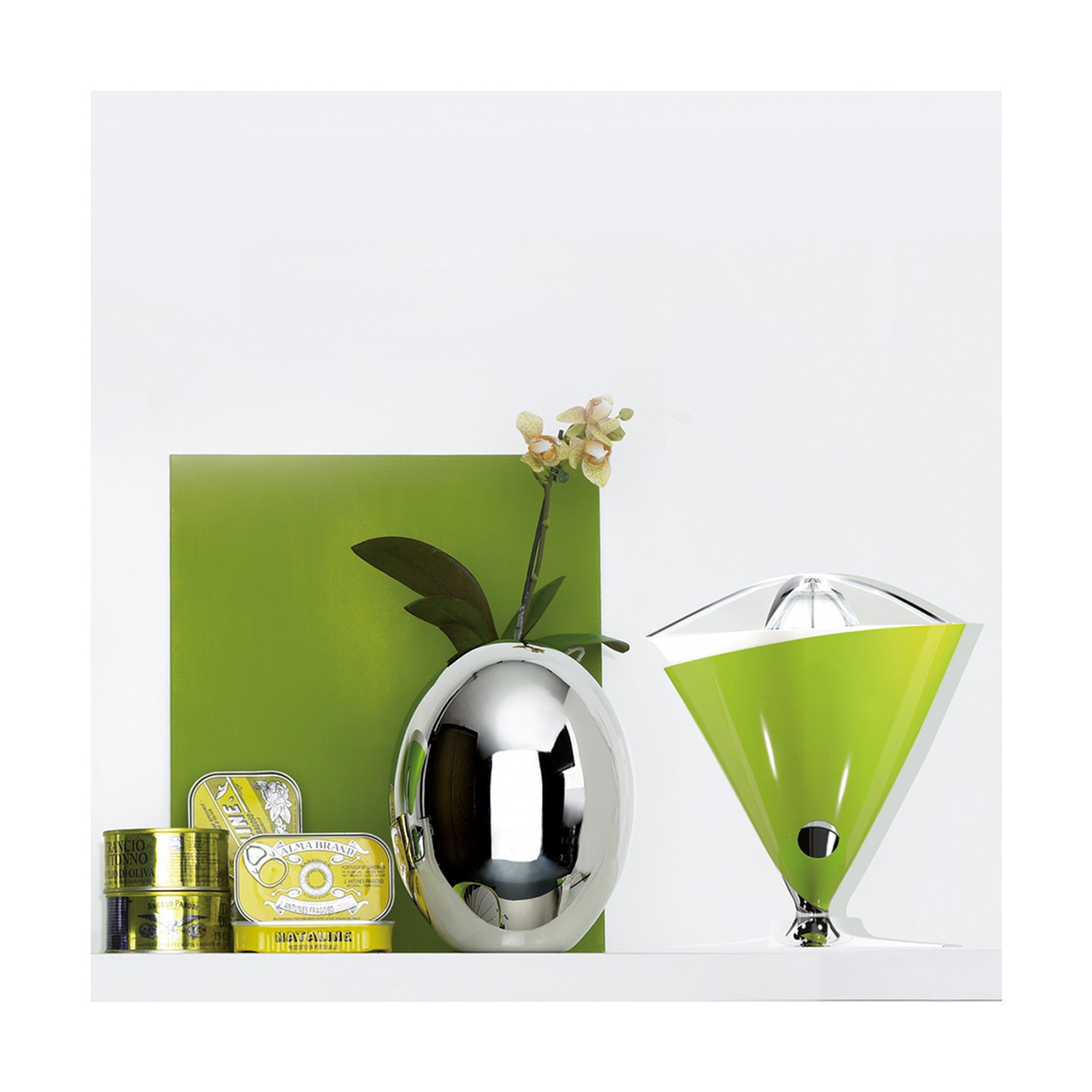 Una natura morta con spremiagrumi verde, vaso d'argento e cibi in scatola.