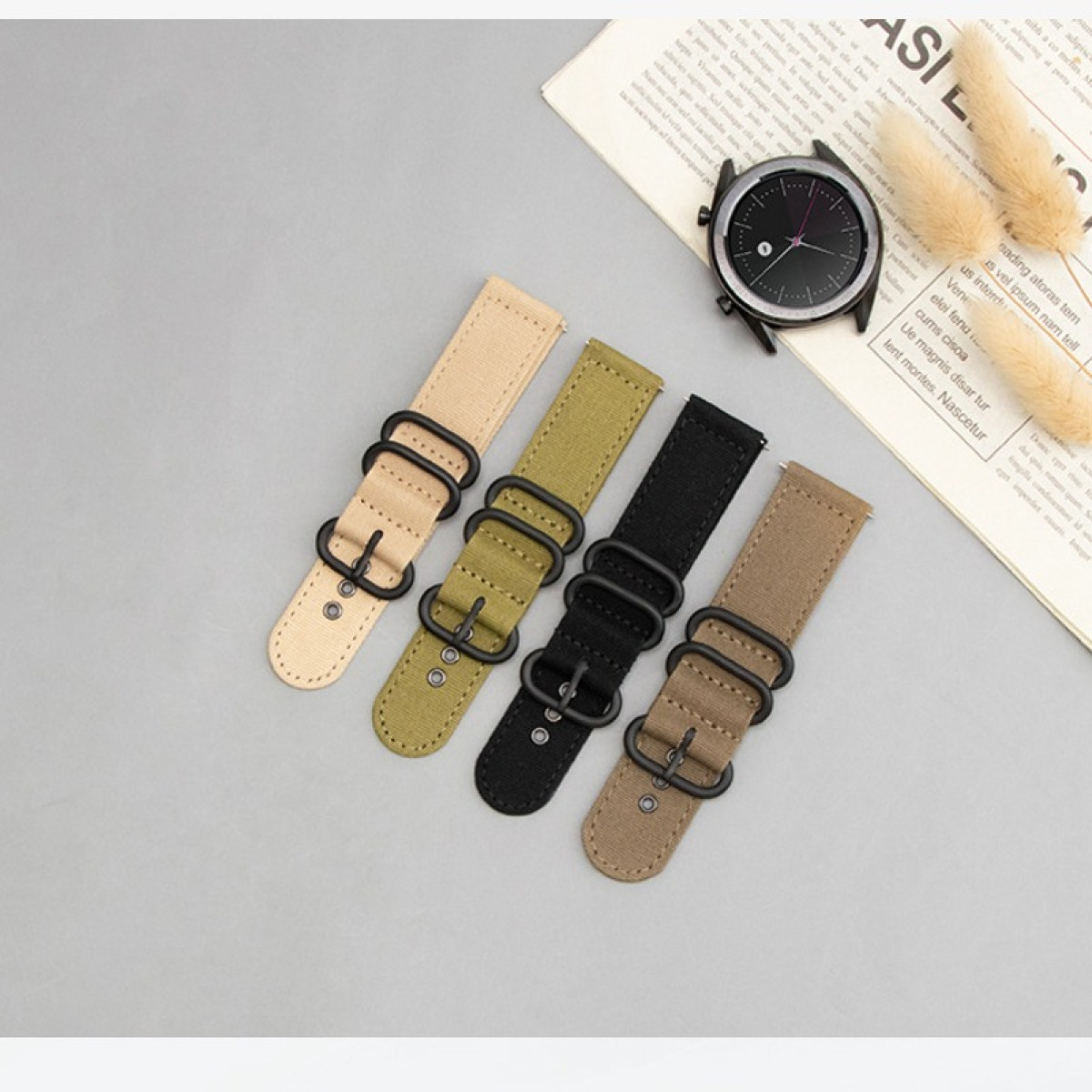 Vier Uhrenarmbänder in Beige, Olive, Schwarz und Braun neben einer Uhr.