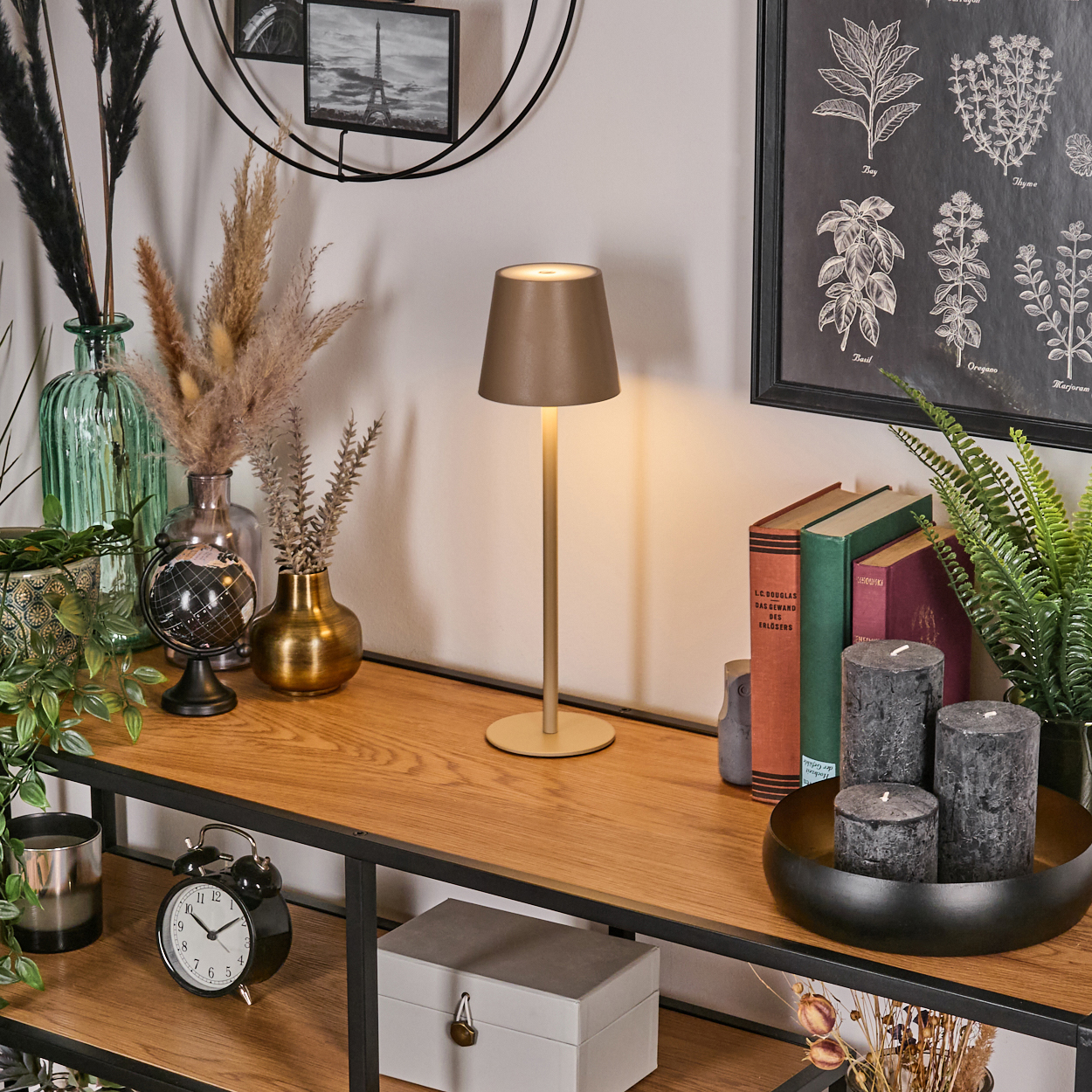 Beige Lampe auf Holzregal mit Deko, darunter Bücher und Kerzen.