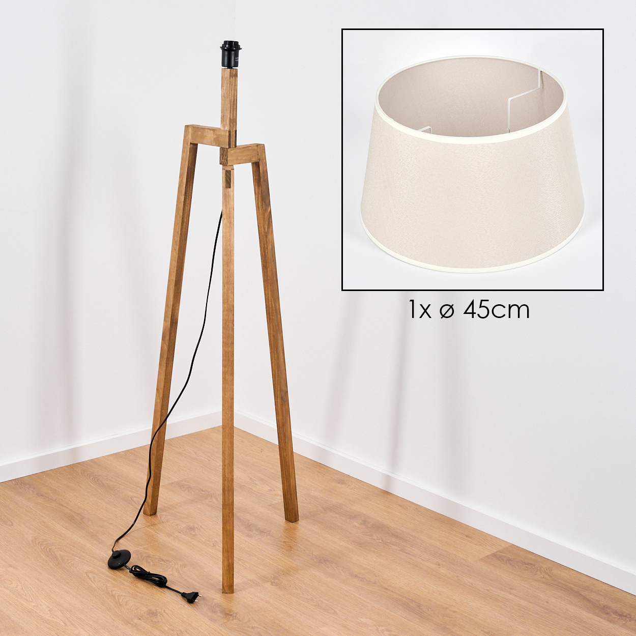 Dreibeinige Holzlampe mit schwarzem Kabel und beigem Lampenschirm, in der Ecke eines Raumes.