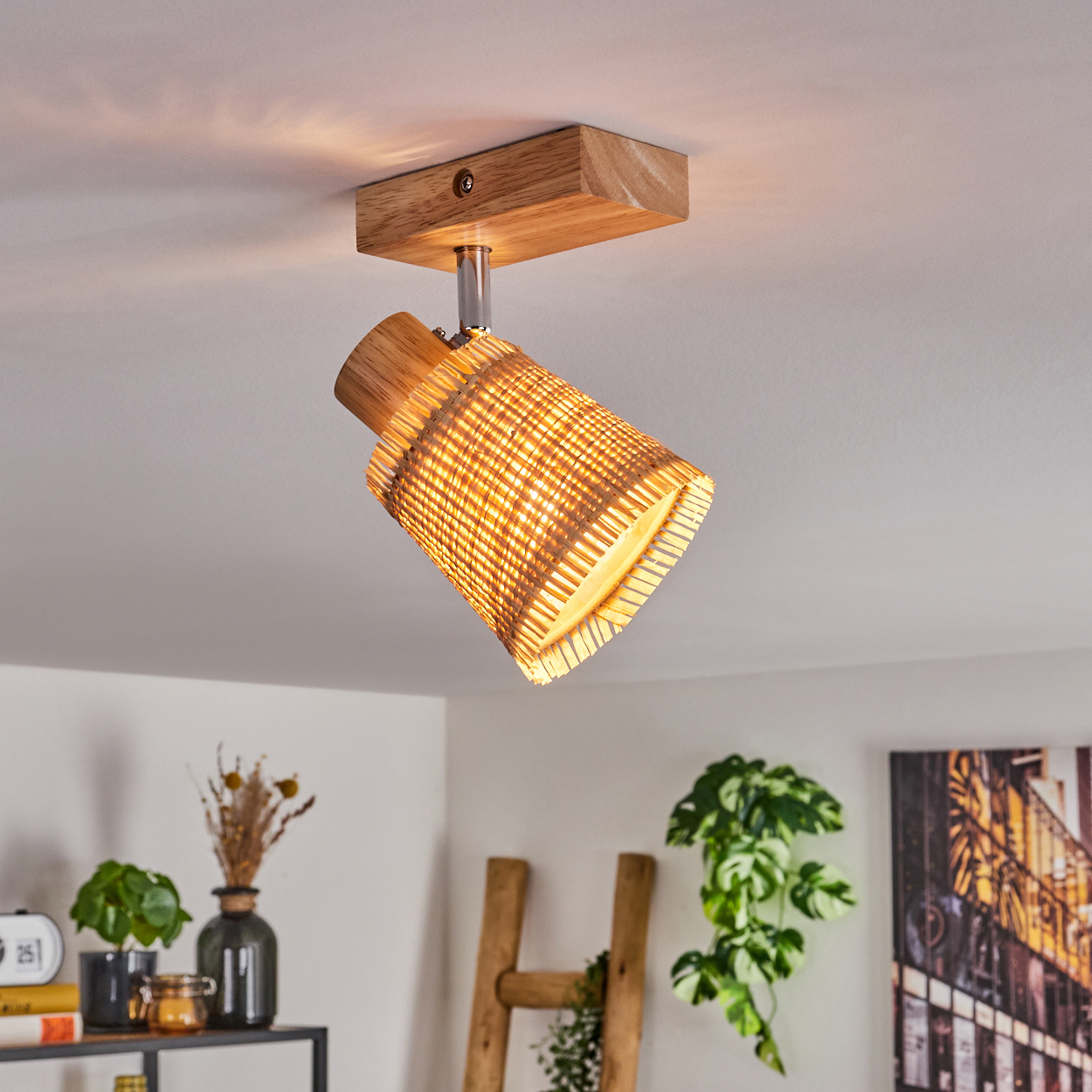Eine Deckenleuchte mit Holzsockel und einem Schirm aus geflochtenem Rattan. Das Licht ist an.