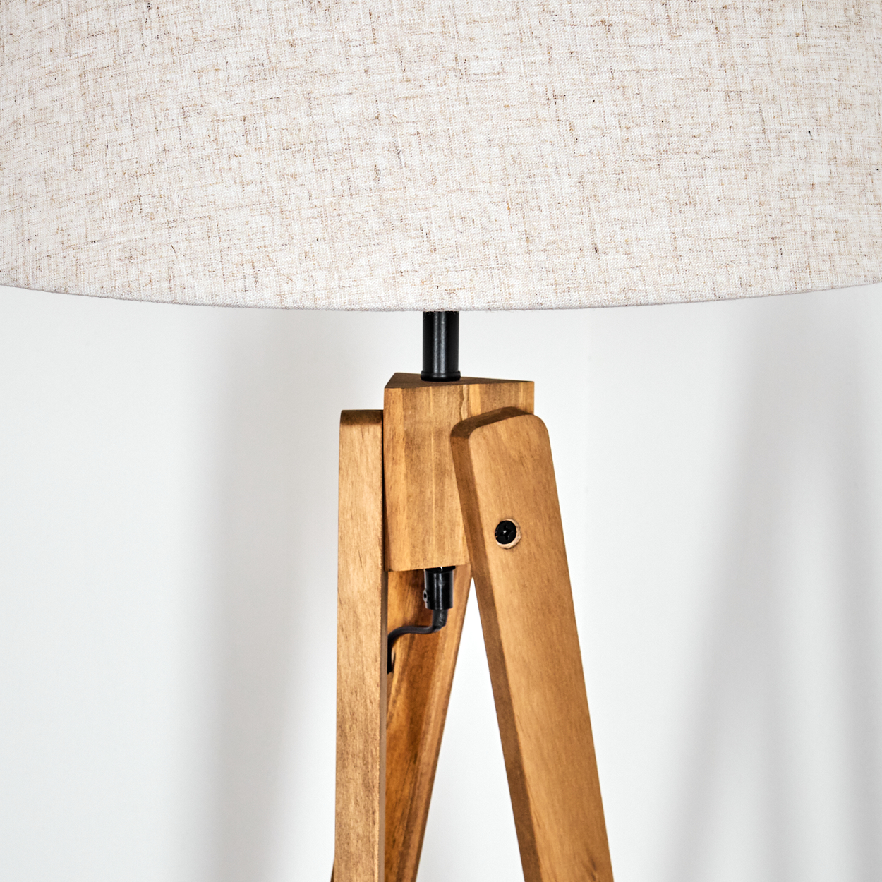 Nahaufnahme eines beigen Stofflampenschirms auf einer hölzernen Stativlampe. Der Stoff hat eine strukturierte Optik.