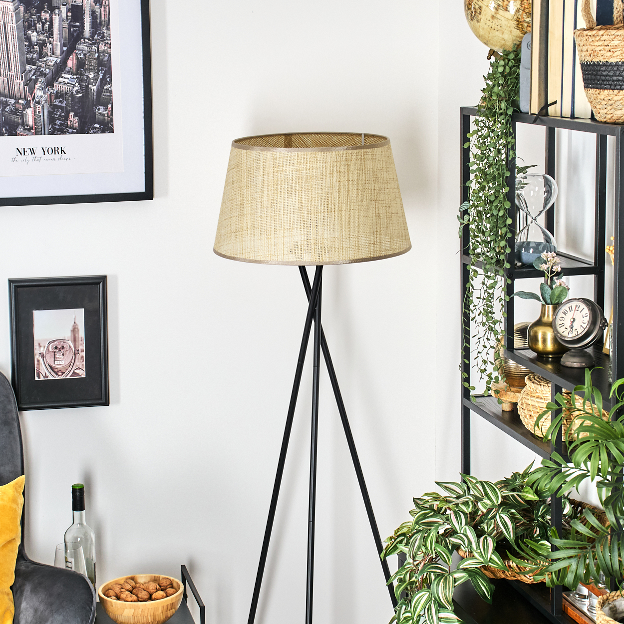 Eine Zimmerecke mit Stehlampe, schwarzem Regal mit Deko und New York Stadtbild.