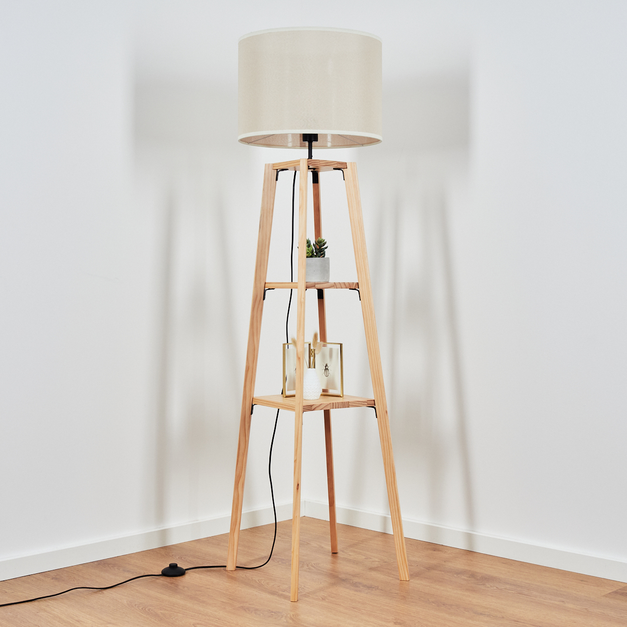 Holz-Stehleuchte mit beigem Lampenschirm, in einer Ecke.