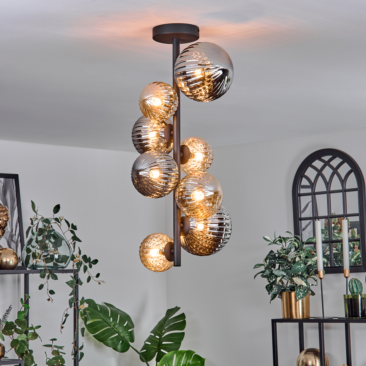 Kronleuchter mit mehreren Glaskugeln. Zimmer mit Pflanzen und Dekorationsartikeln.