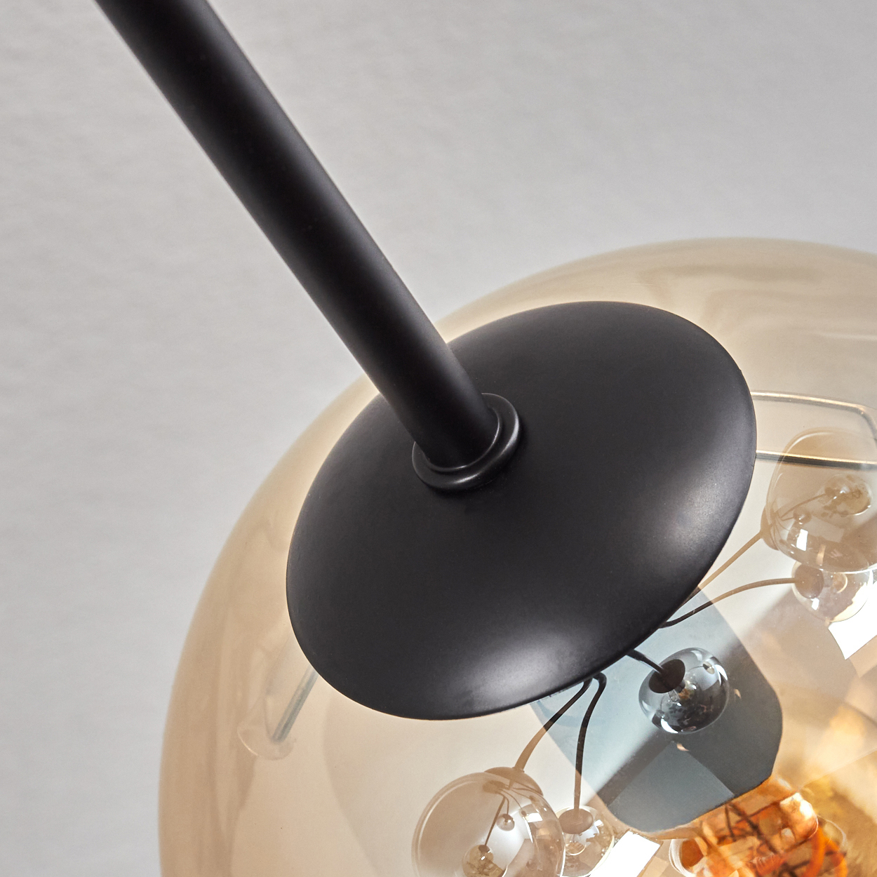 Nahaufnahme einer Glaskugel mit Glühbirne, an der ein schwarzer Arm befestigt ist.