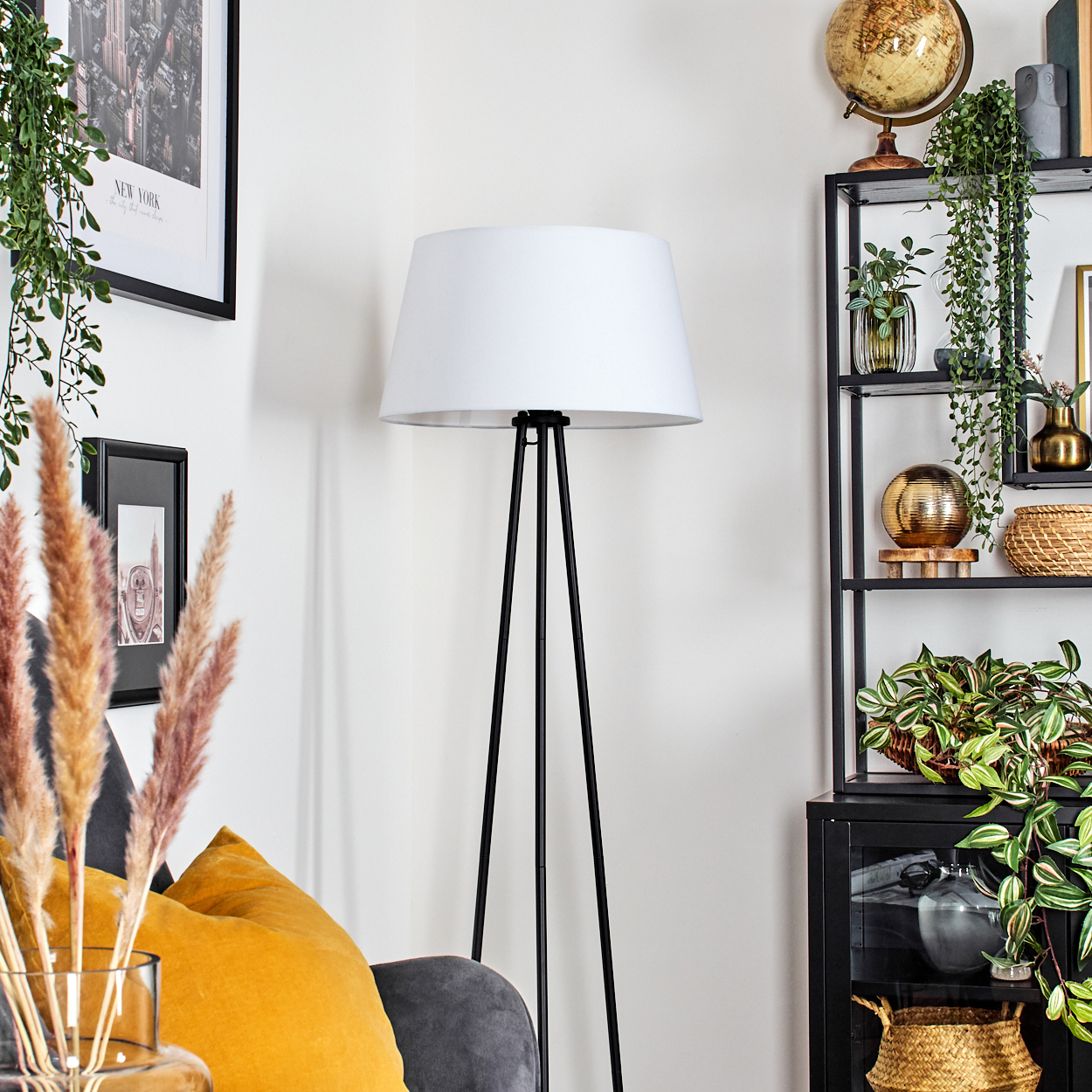 Eine Stehlampe mit weißem Schirm in einem Wohnzimmer.