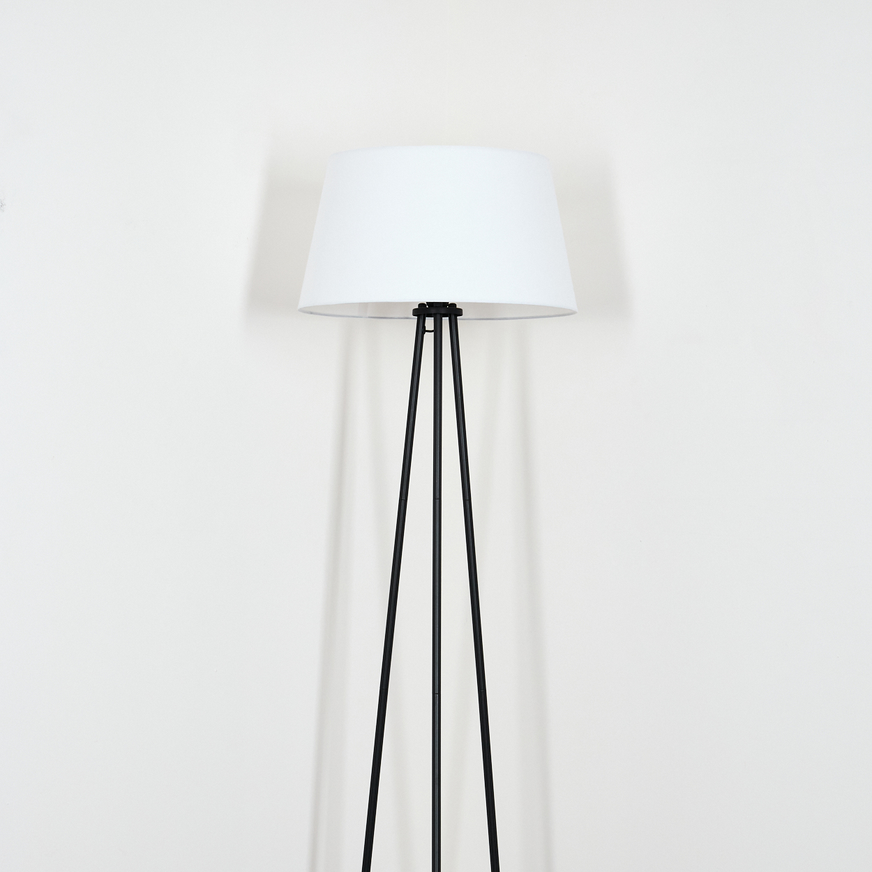 Eine Stehlampe mit weißem Schirm auf weißem Hintergrund.