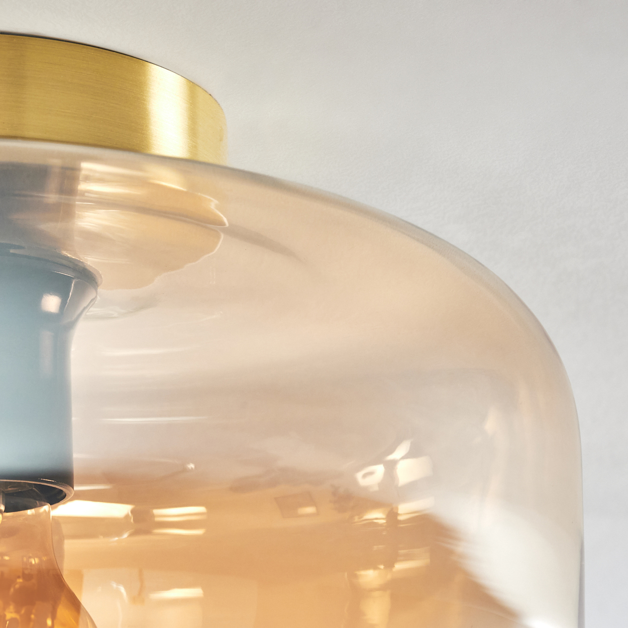 Nahaufnahme einer Leuchte mit Glasschirm und goldenem Sockel, und einem blauen Element.
