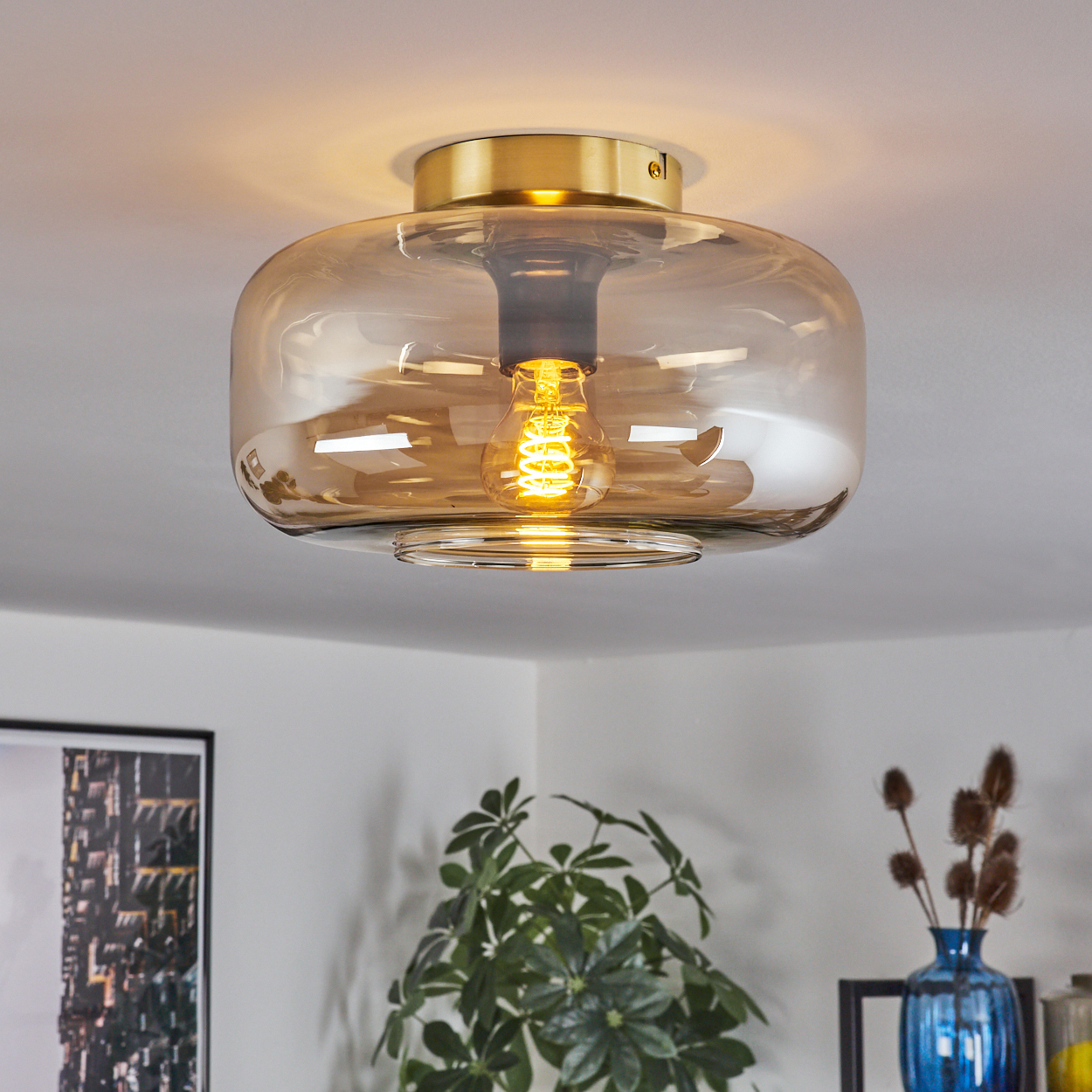 Deckenleuchte, orangefarbener Glasschirm, goldener Sockel, leuchtende Glühbirne. Inneneinrichtung, gemütliche Atmosphäre.