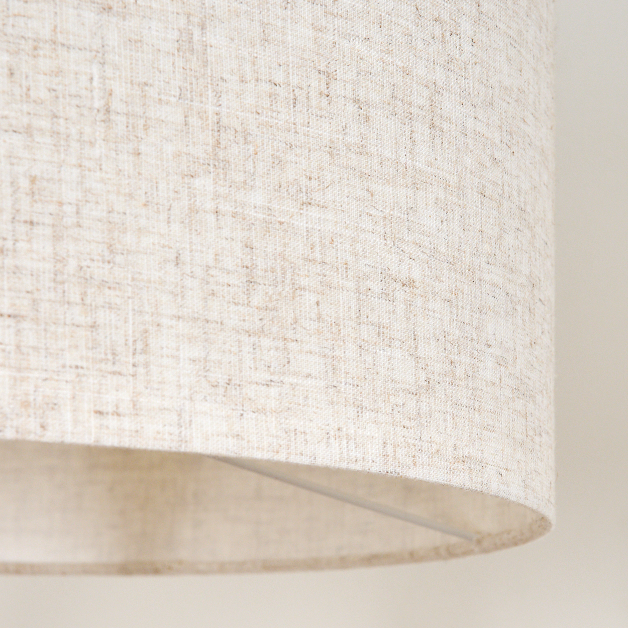 Cremefarbener Lampenschirmstoff, Nahaufnahme. Strukturierte Oberfläche, neutraler Ton, schlichtes Design.