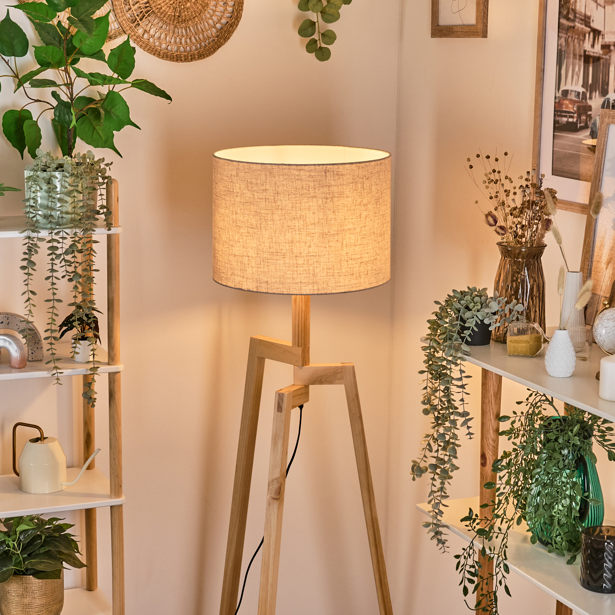 Hölzerne Stativ-Stehlampe mit Leinen-Lampenschirm, in einem Raum mit Pflanzen und Deko.