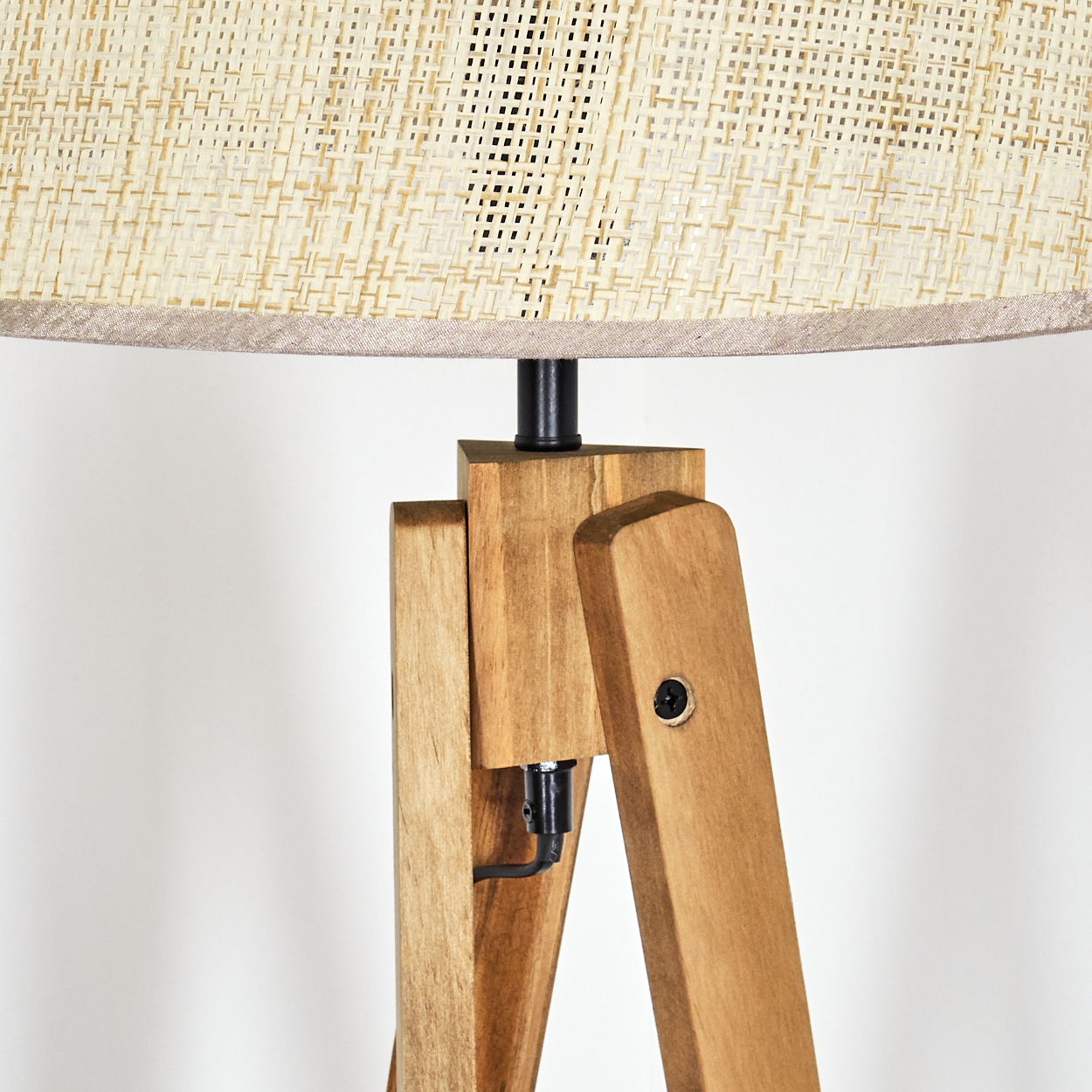 Nahaufnahme des Lampenfußes einer Holz-Dreibein-Lampe mit beigem Lampenschirm.
