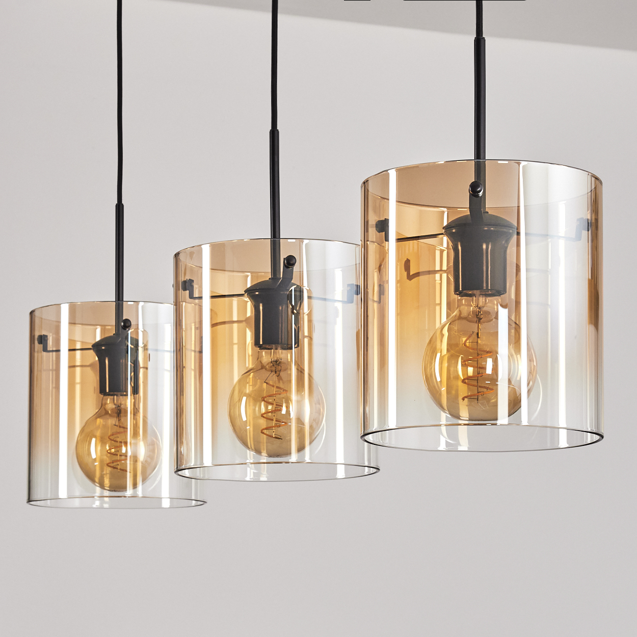 Drei hängende Lampen. Jede hat einen Glaszylinder. Die Glühbirnen sind sichtbar.