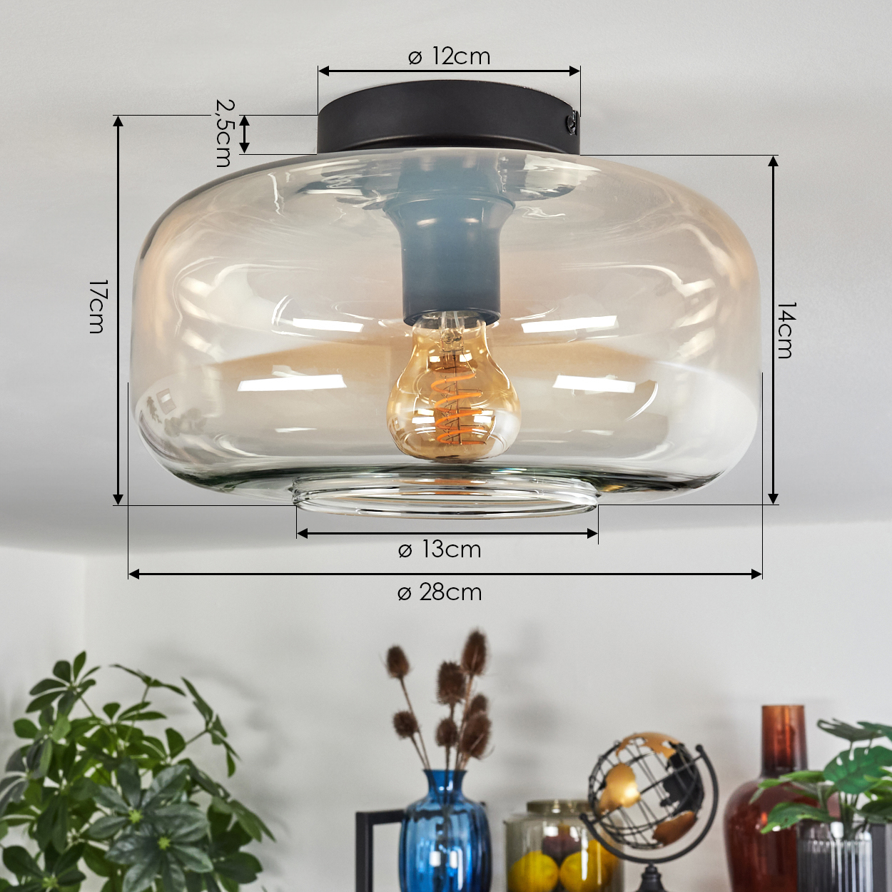 Eine Deckenlampe mit geschwungenem bernsteinfarbenem Glasschirm. Die Abmessungen der Lampe sind angegeben und die Glühbirne ist sichtbar.