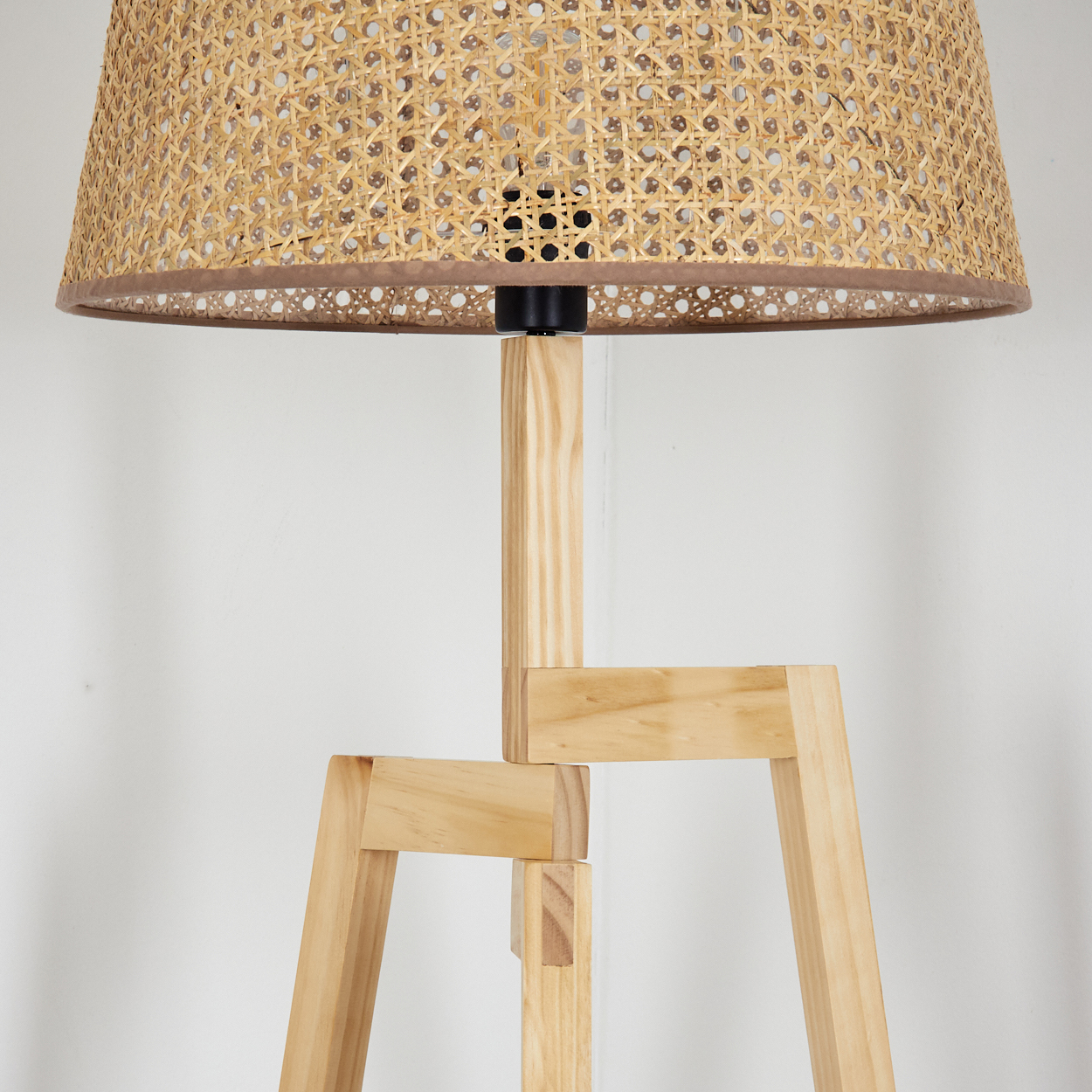 Eine Stehlampe aus Holz mit einem gewebten Lampenschirm.